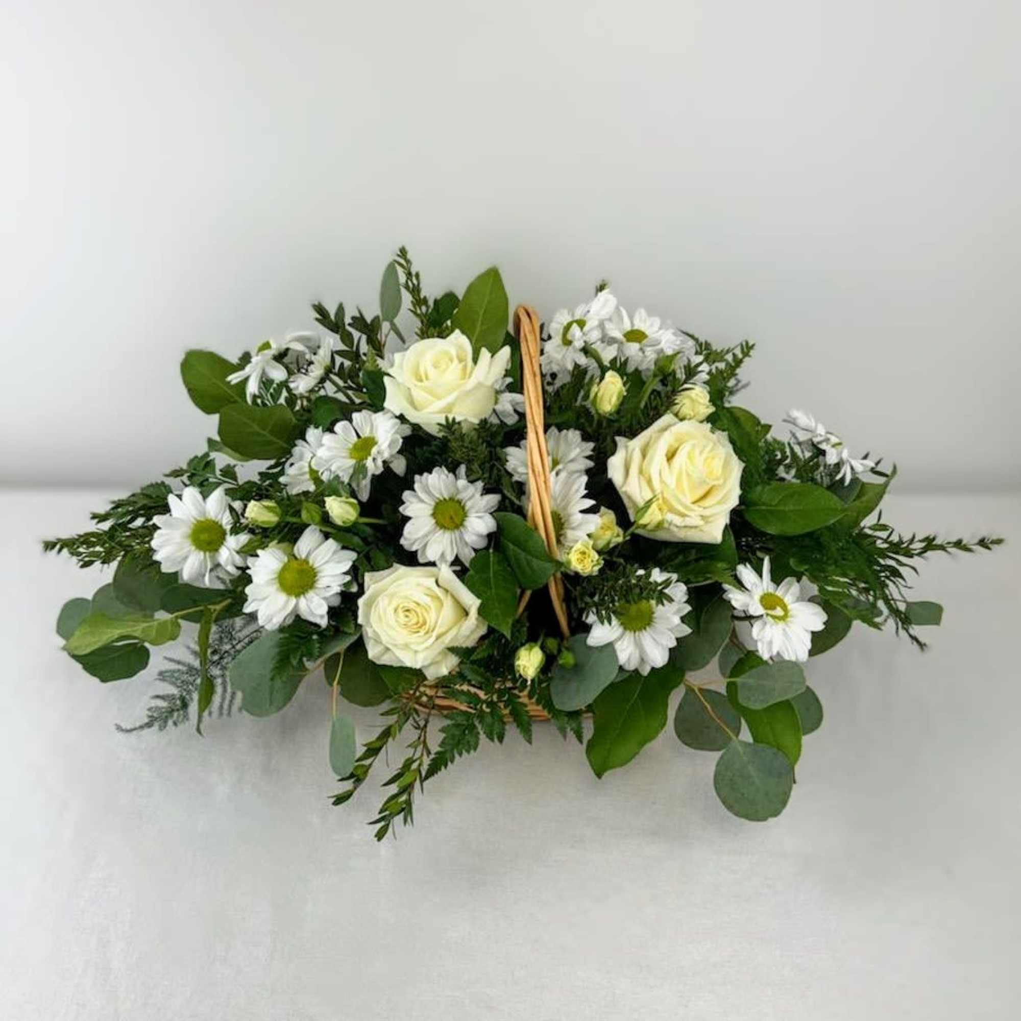 A peaceful white and green basket featuring white daisy mums and white