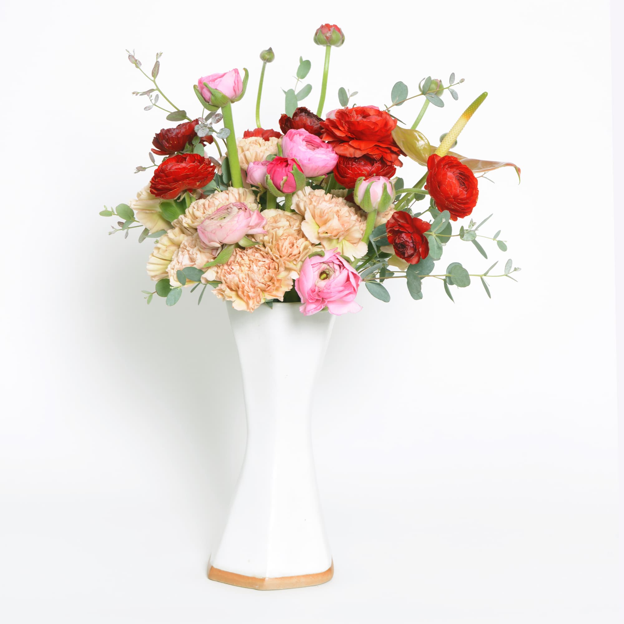 An arrangement of red, pink and peach in a handmade ceramic angular