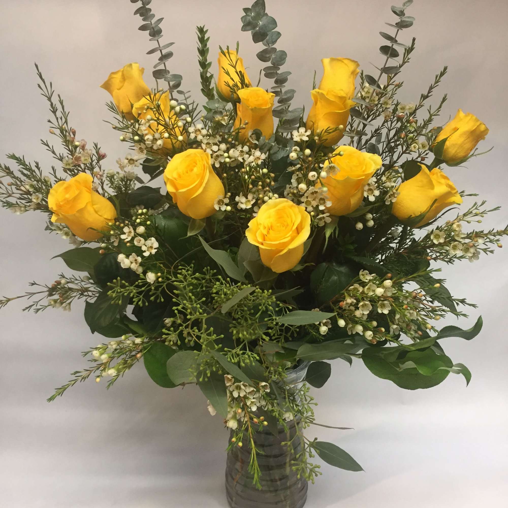 Beautiful Bright yellow roses in a medium clear vase with the variety