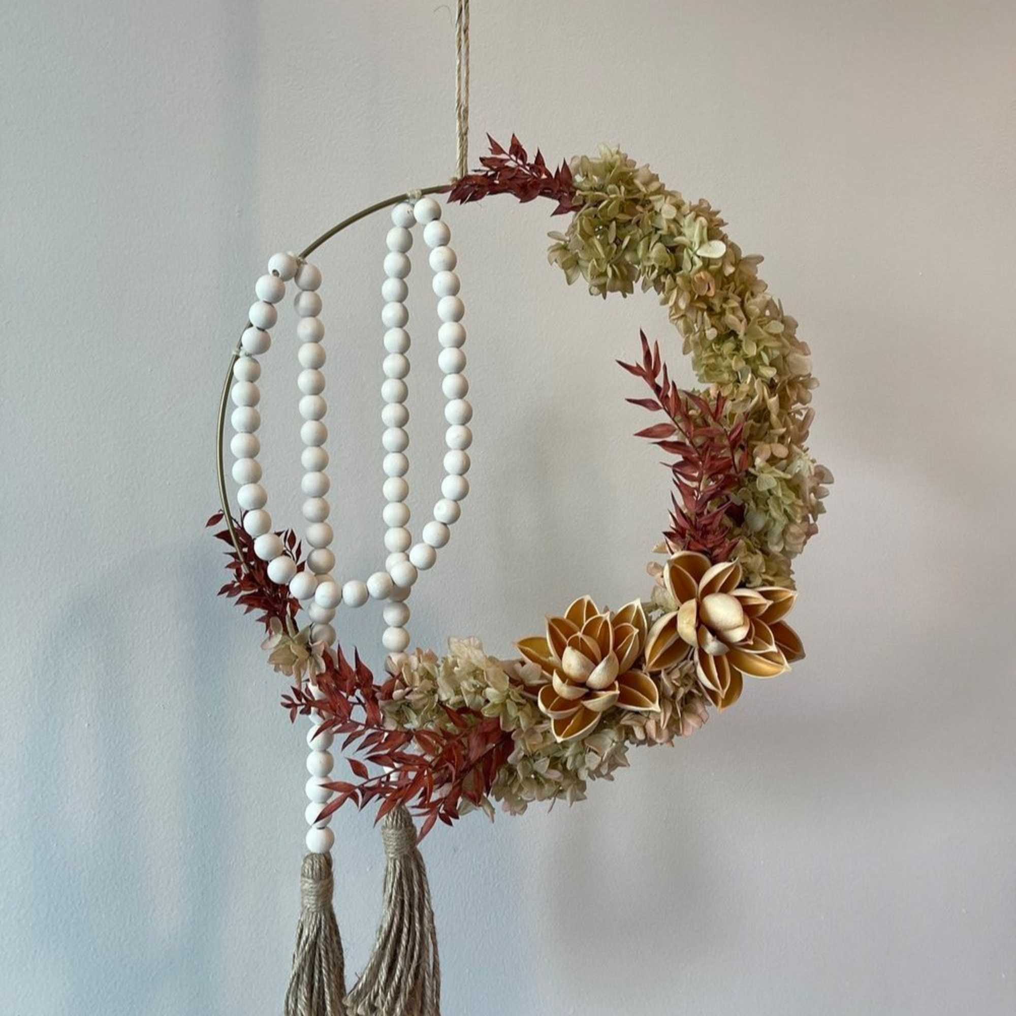 - Hanging floral arrangement with circular design
- Pale red blooms and verdant