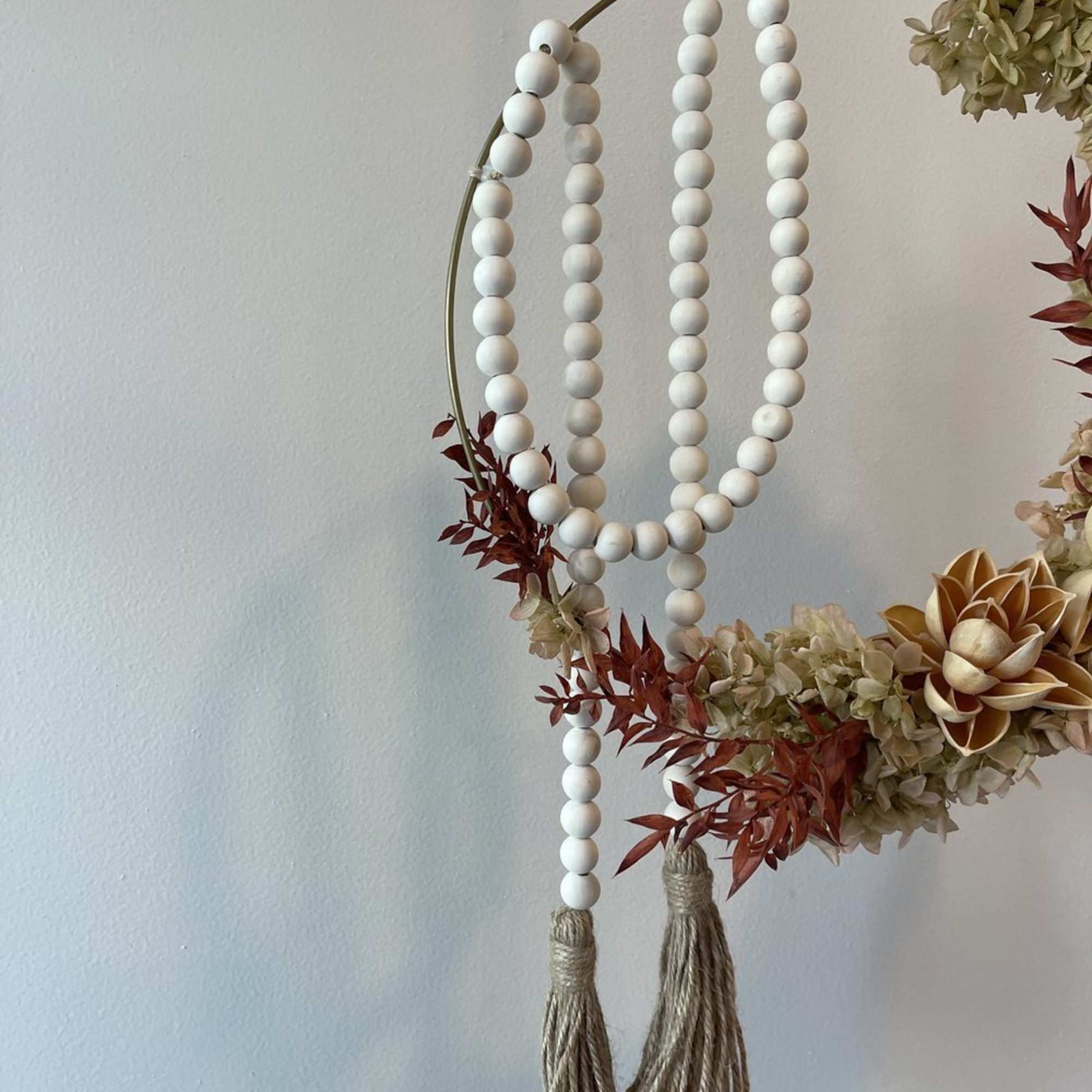 - Hanging floral arrangement with circular design
- Pale red blooms and verdant