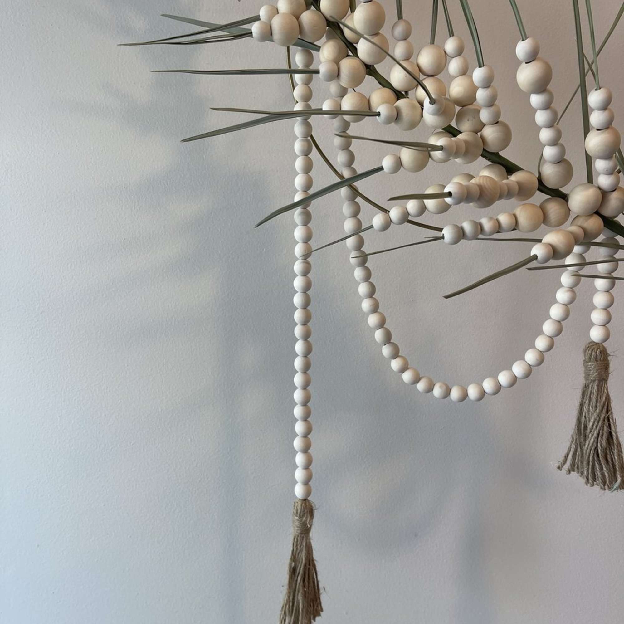 - Circular hanging floral arrangement with graceful palm frond
- Intertwined with delicate