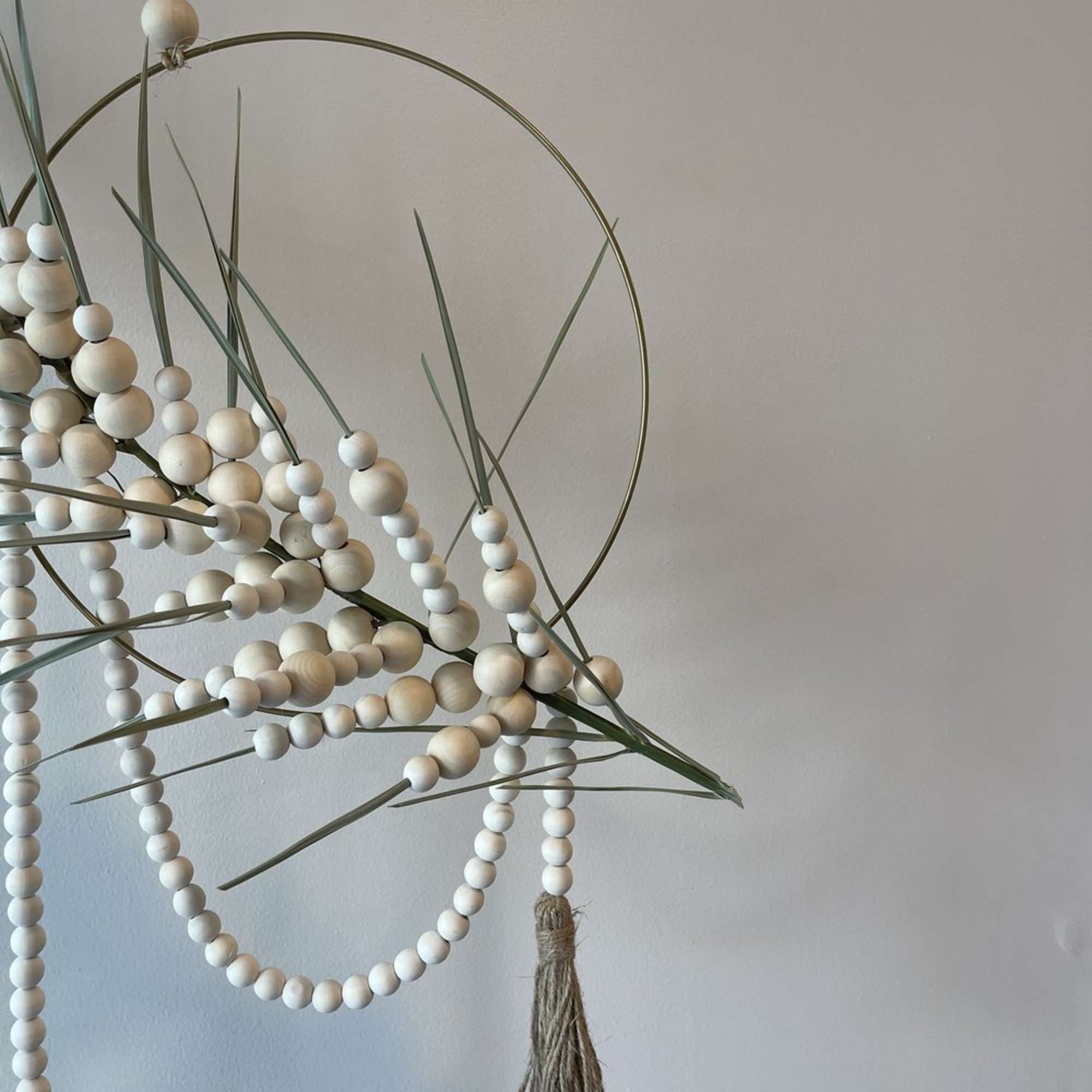 - Circular hanging floral arrangement with graceful palm frond
- Intertwined with delicate