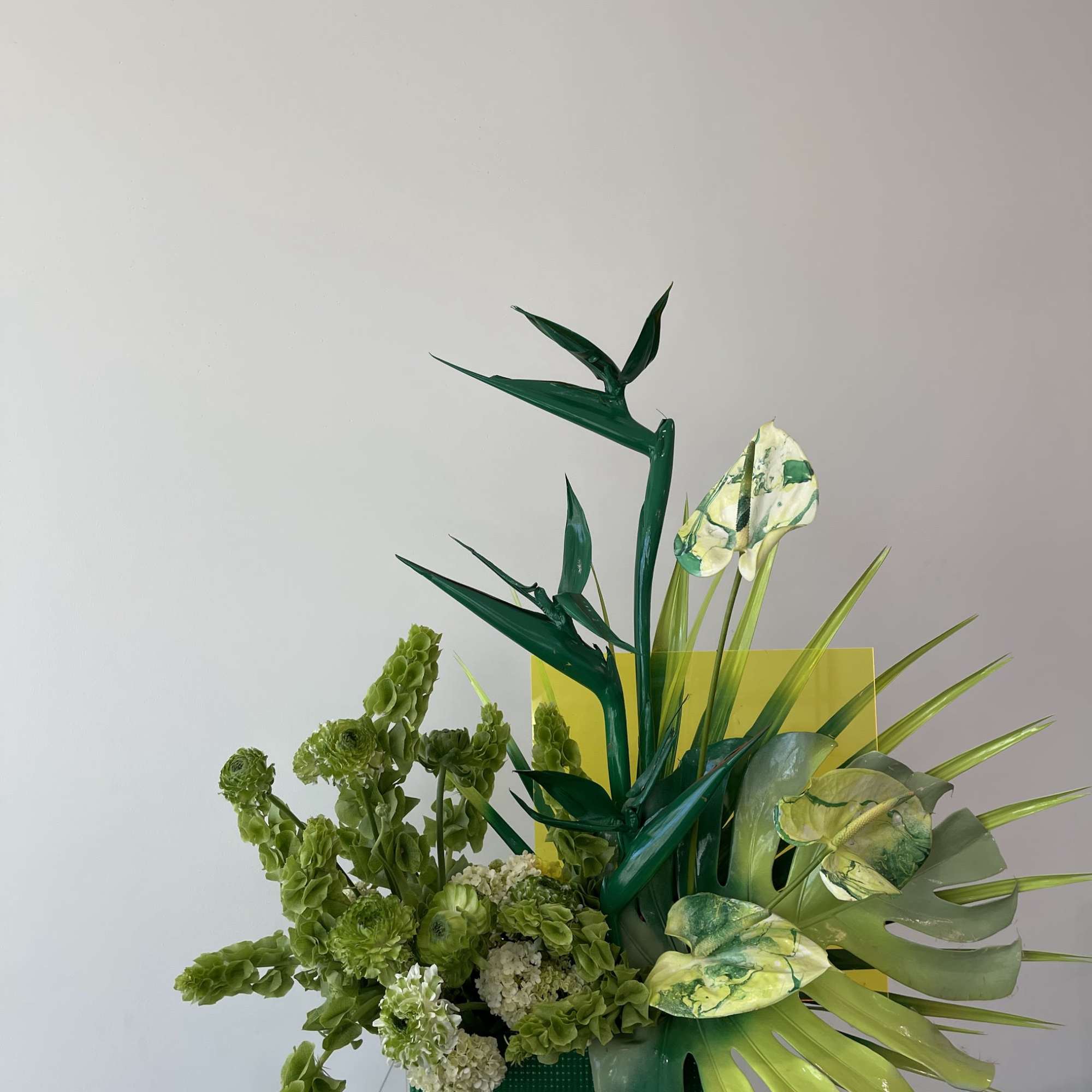 - Tall, striking arrangement with lush green foliage
- Bold spray-painted green leaves