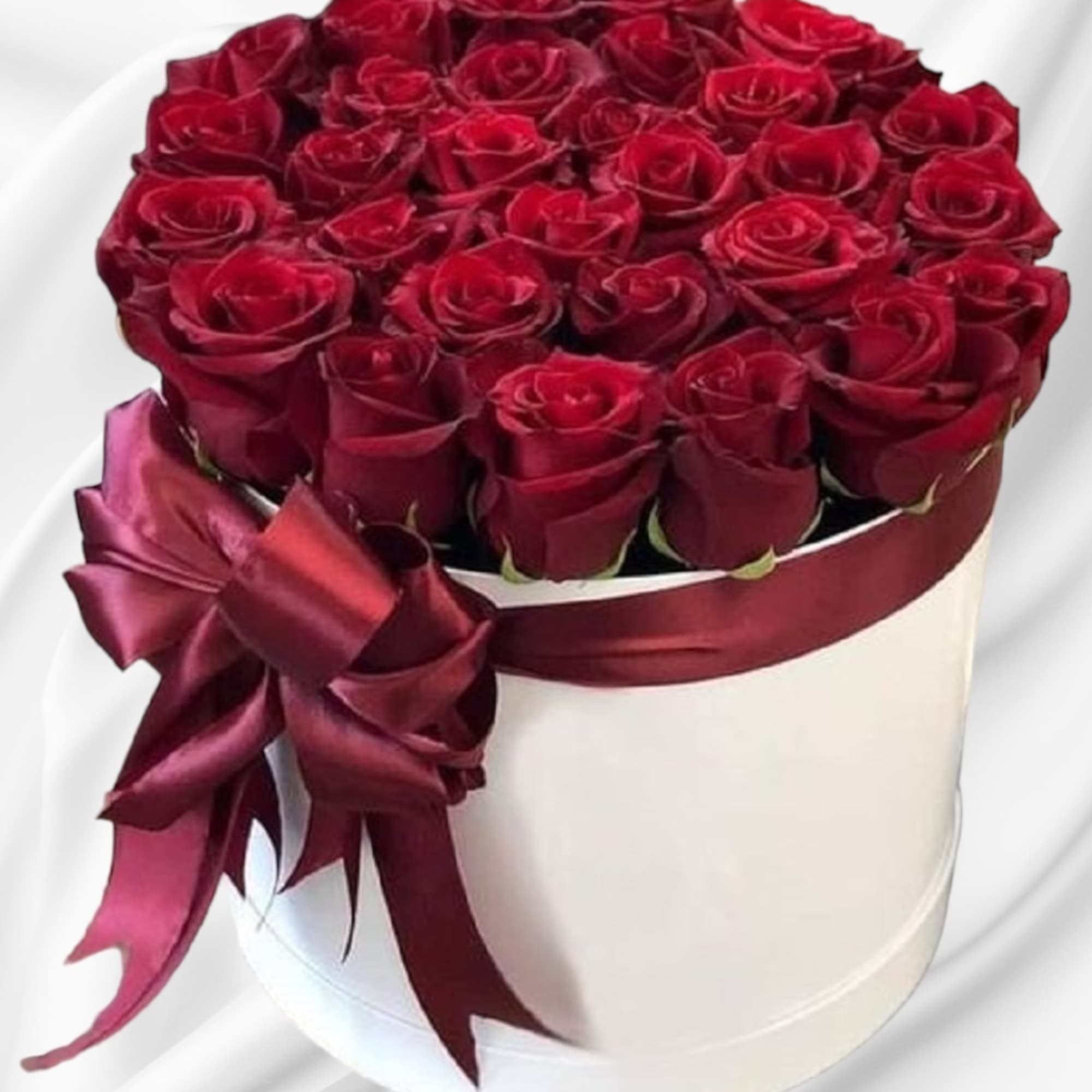 Red roses are beautifully arranged in a white cylinder box. Have them