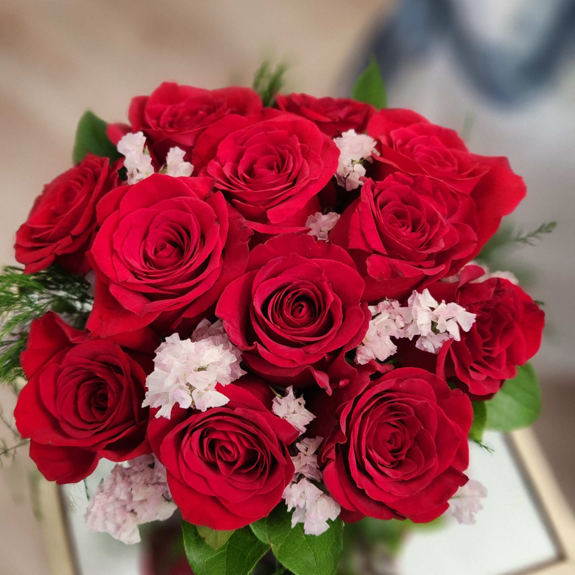 A beautifully designed dozen of red roses in a red cube container A beautifully designed dozen of red roses in a red cube container