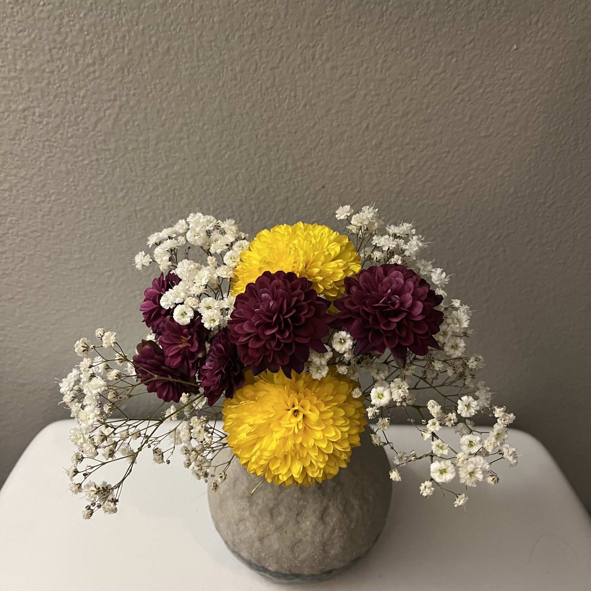 This mini bouquet features chrysanthemums (mums) paired with baby breath flowers. It