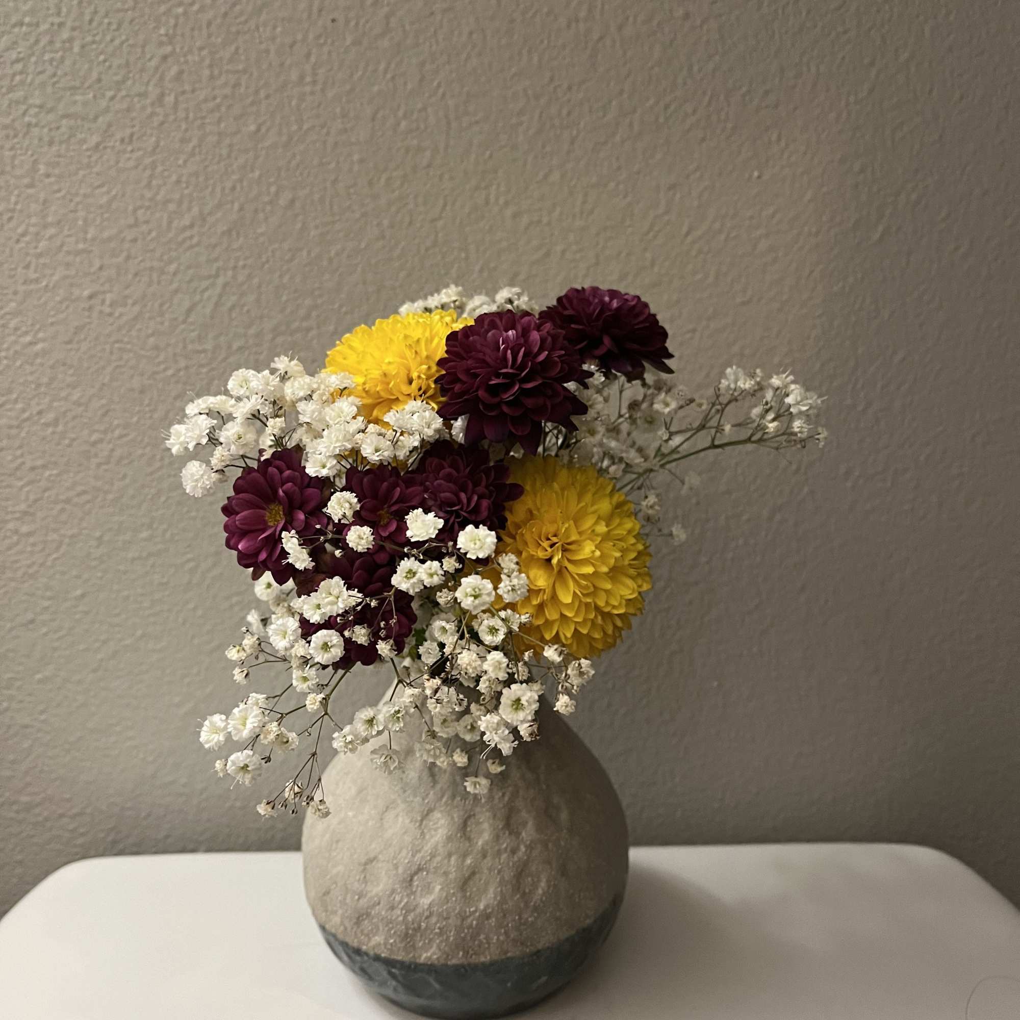 This mini bouquet features chrysanthemums (mums) paired with baby breath flowers. It