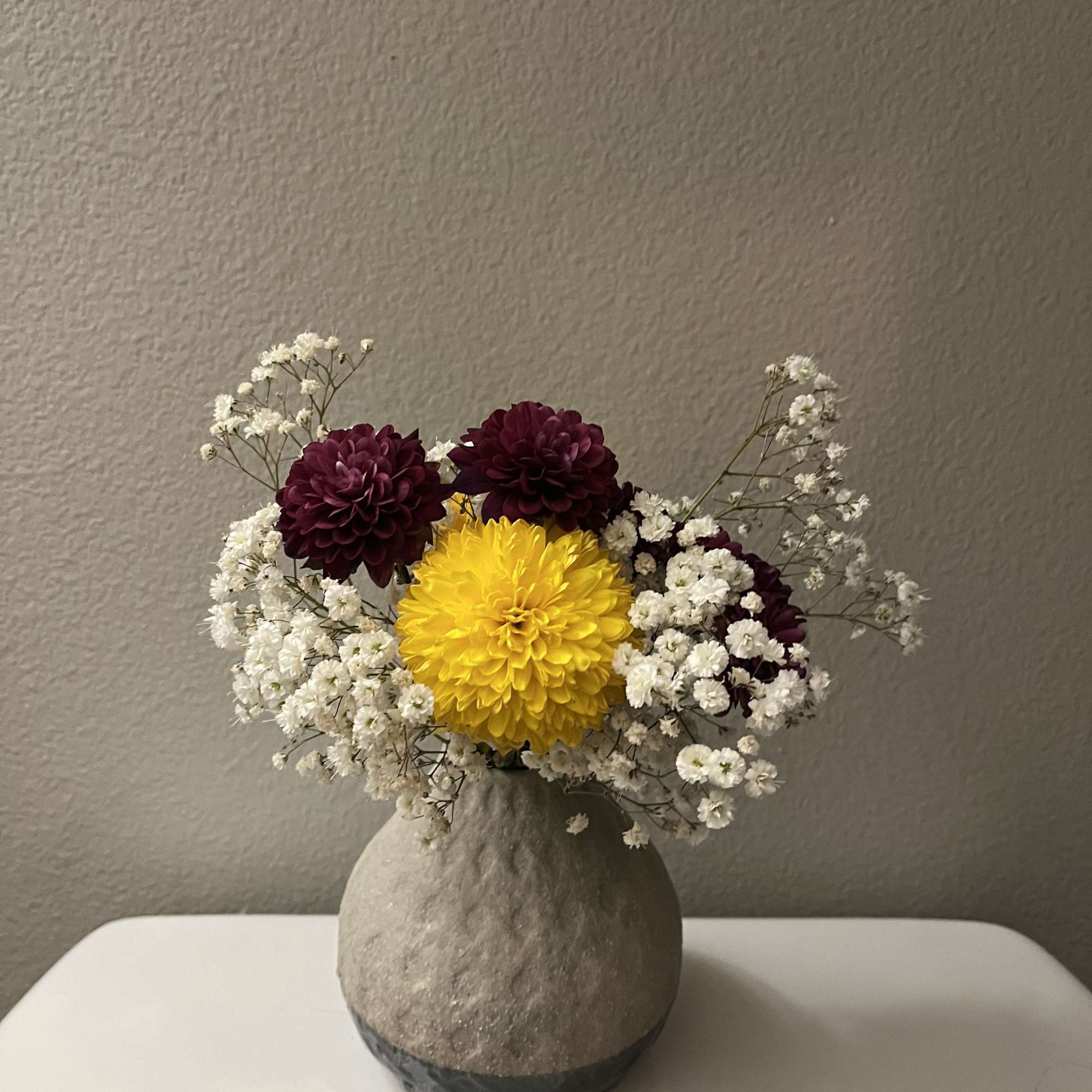 This mini bouquet features chrysanthemums (mums) paired with baby breath flowers. It