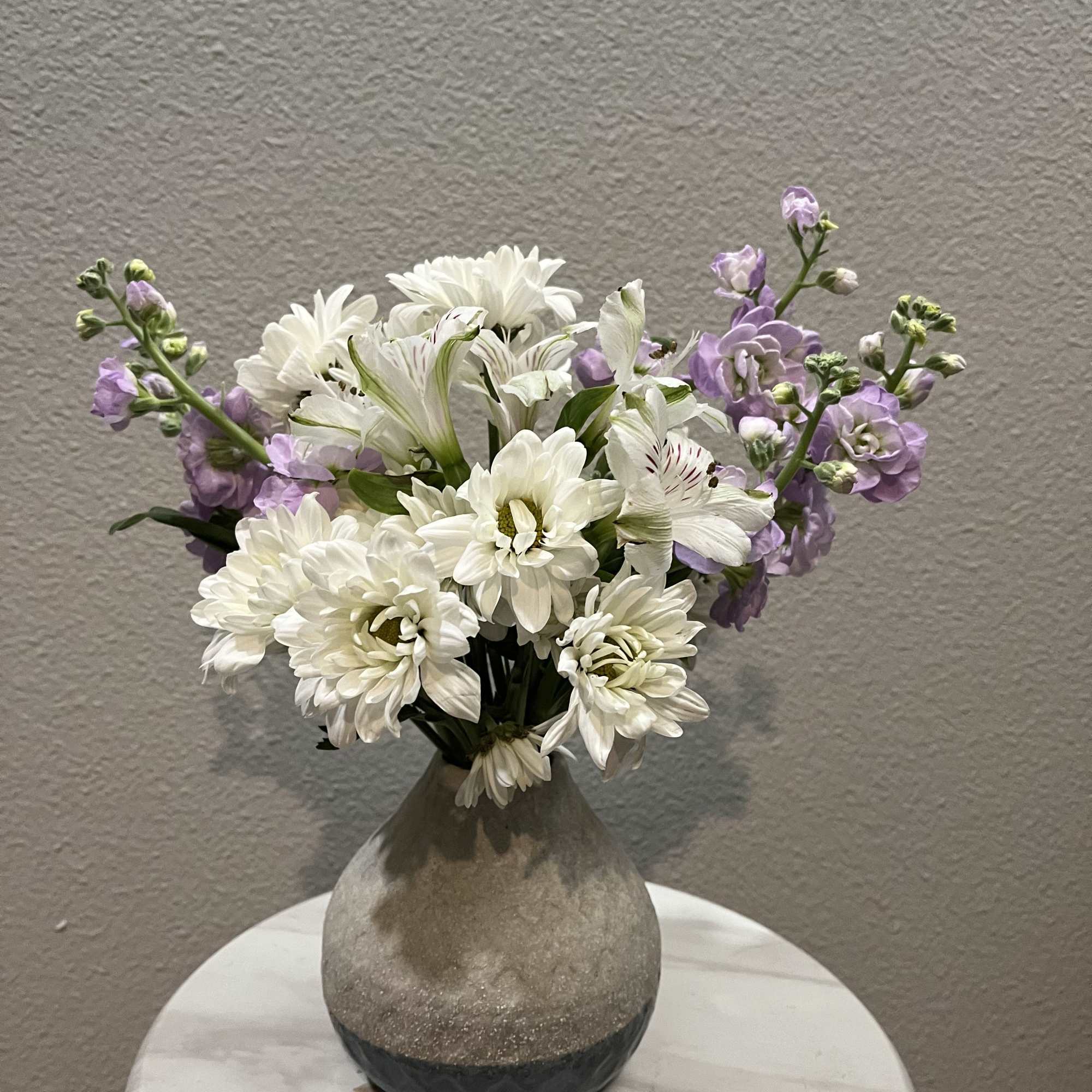 This mini bouquet features chrysanthemums (mums) paired with purple masa. It is