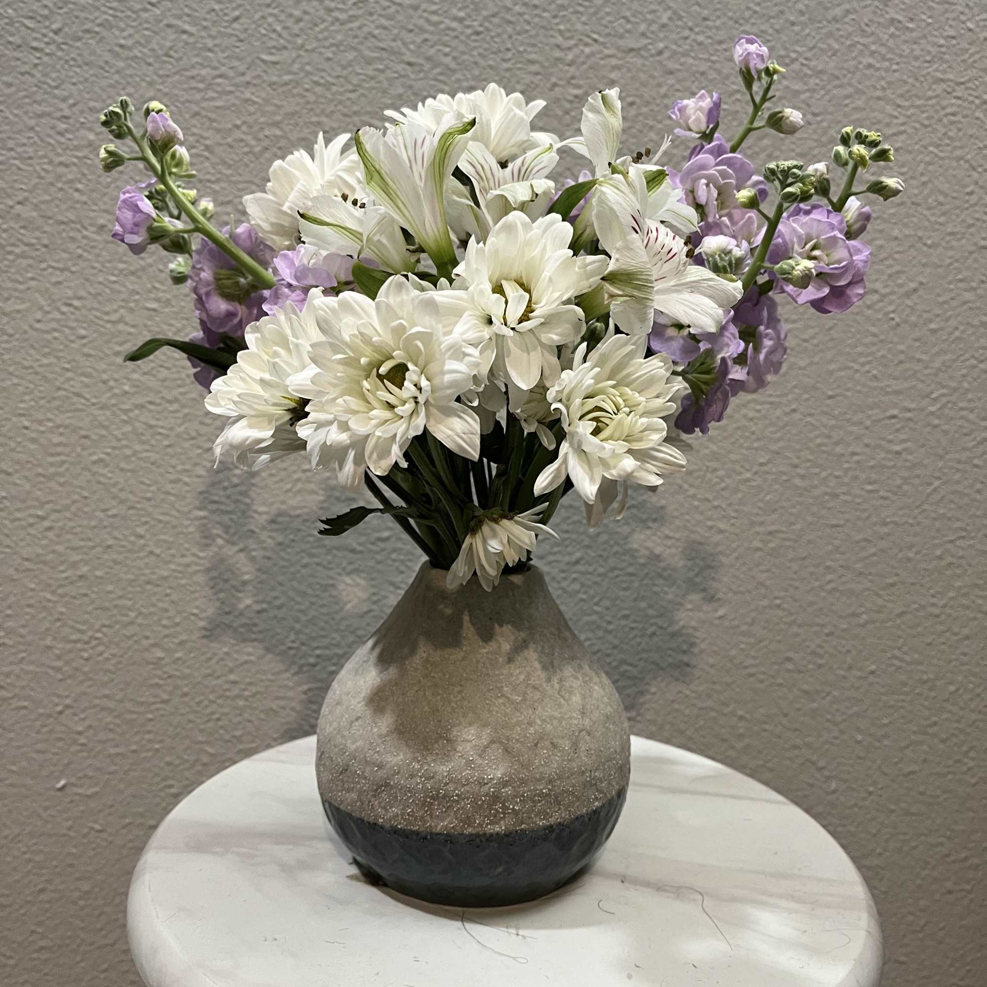 This mini bouquet features chrysanthemums (mums) paired with purple masa. It is