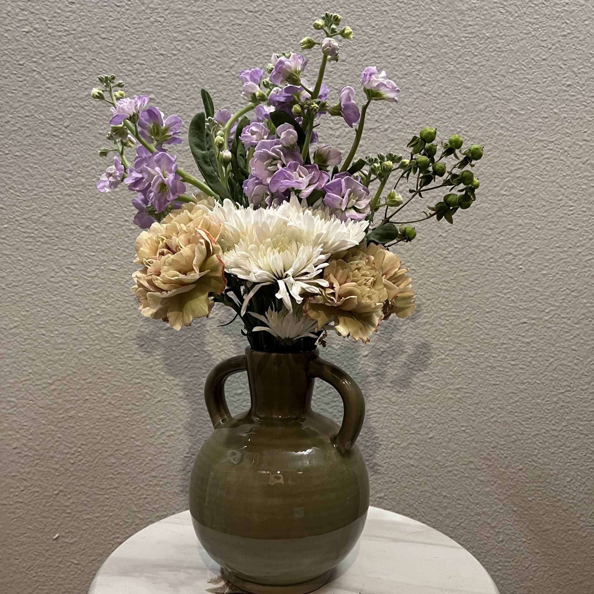 This mini bouquet features chrysanthemums (mums) paired with marigolds and mesa flowers.