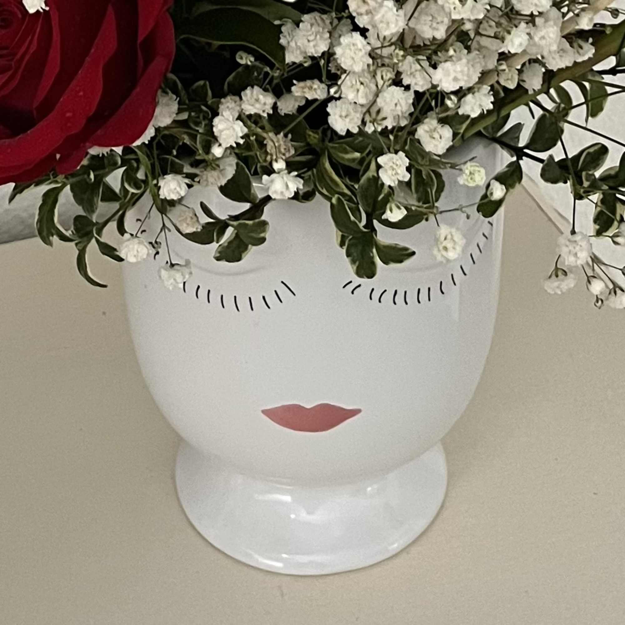 Pink and red bouquet in a ceramic head vase.
Pink head vase is