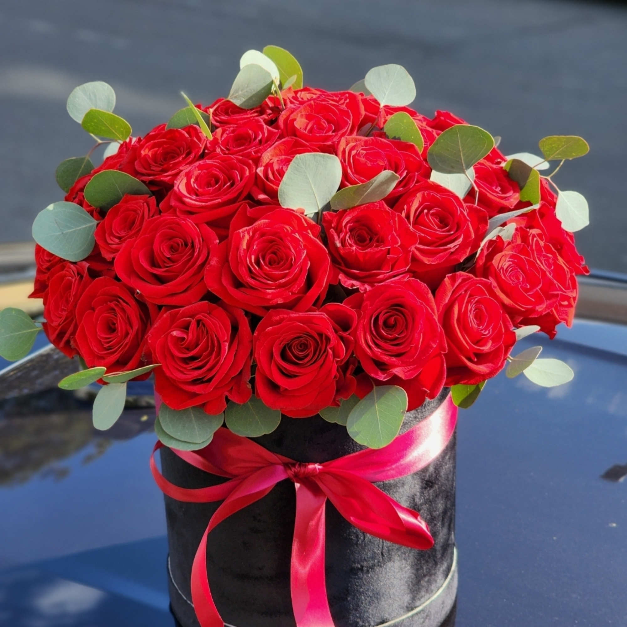 Delicate red roses cradled in a hatbox, a flawless expression of affection
