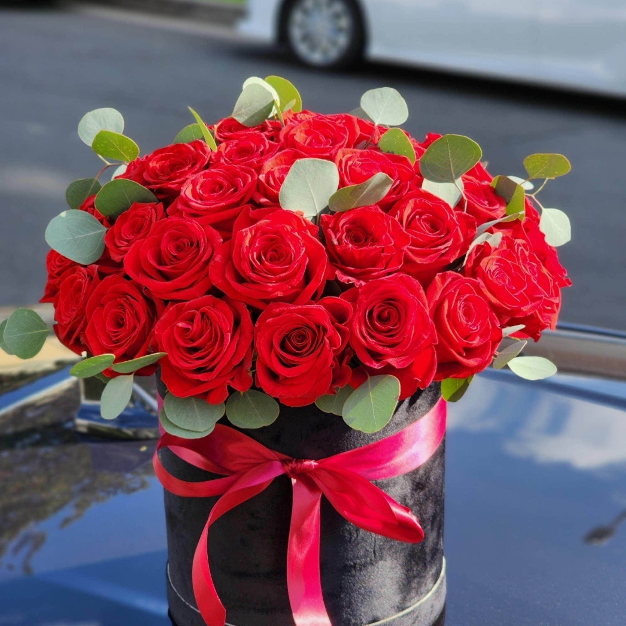 Delicate red roses cradled in a hatbox, a flawless expression of affection