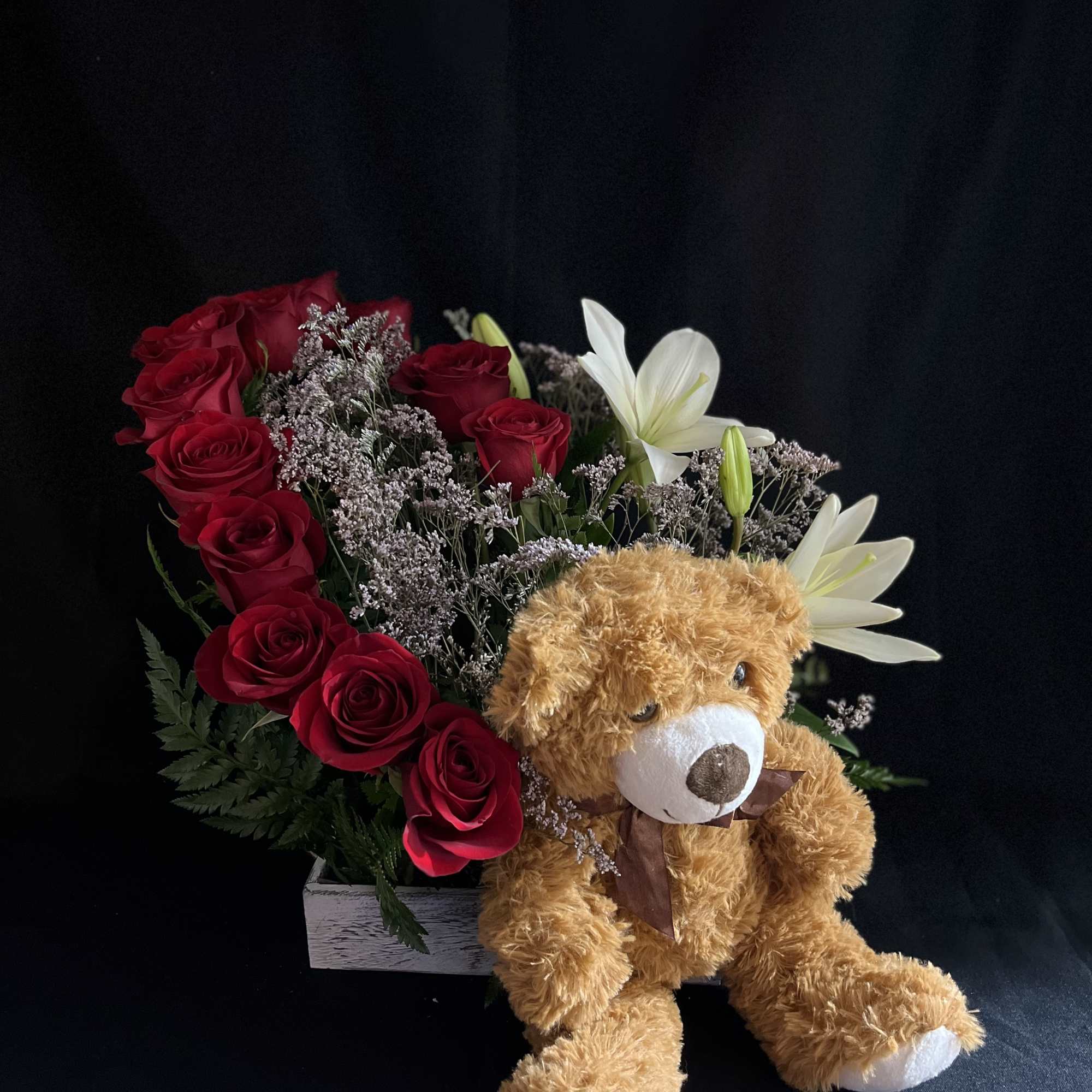 A dozen roses, lilies, with limonium, green foliage and a teddy bear.