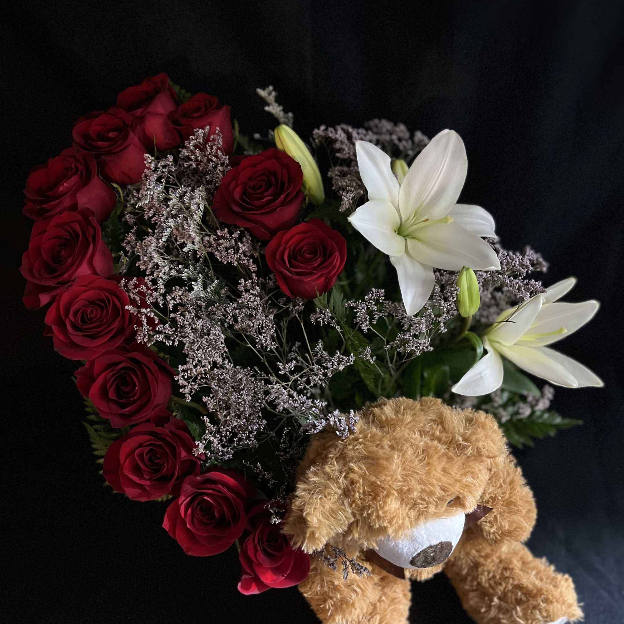 A dozen roses, lilies, with limonium, green foliage and a teddy bear.