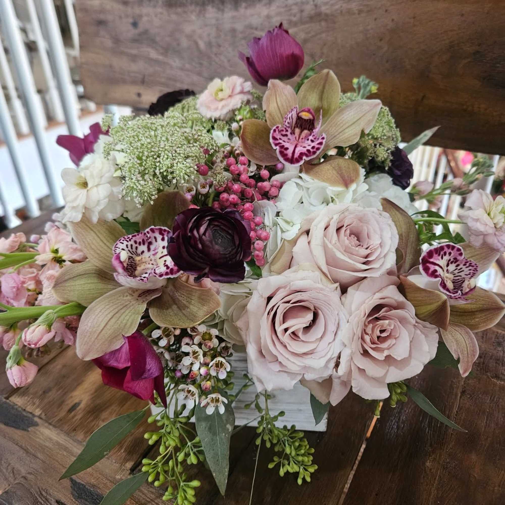 Roses, cymbidium orchids, hydrangea, pink stock, ranunculus, tulips, wax flower, berries, seeded Roses, cymbidium orchids, hydrangea, pink stock, ranunculus, tulips, wax flower, berries, seeded