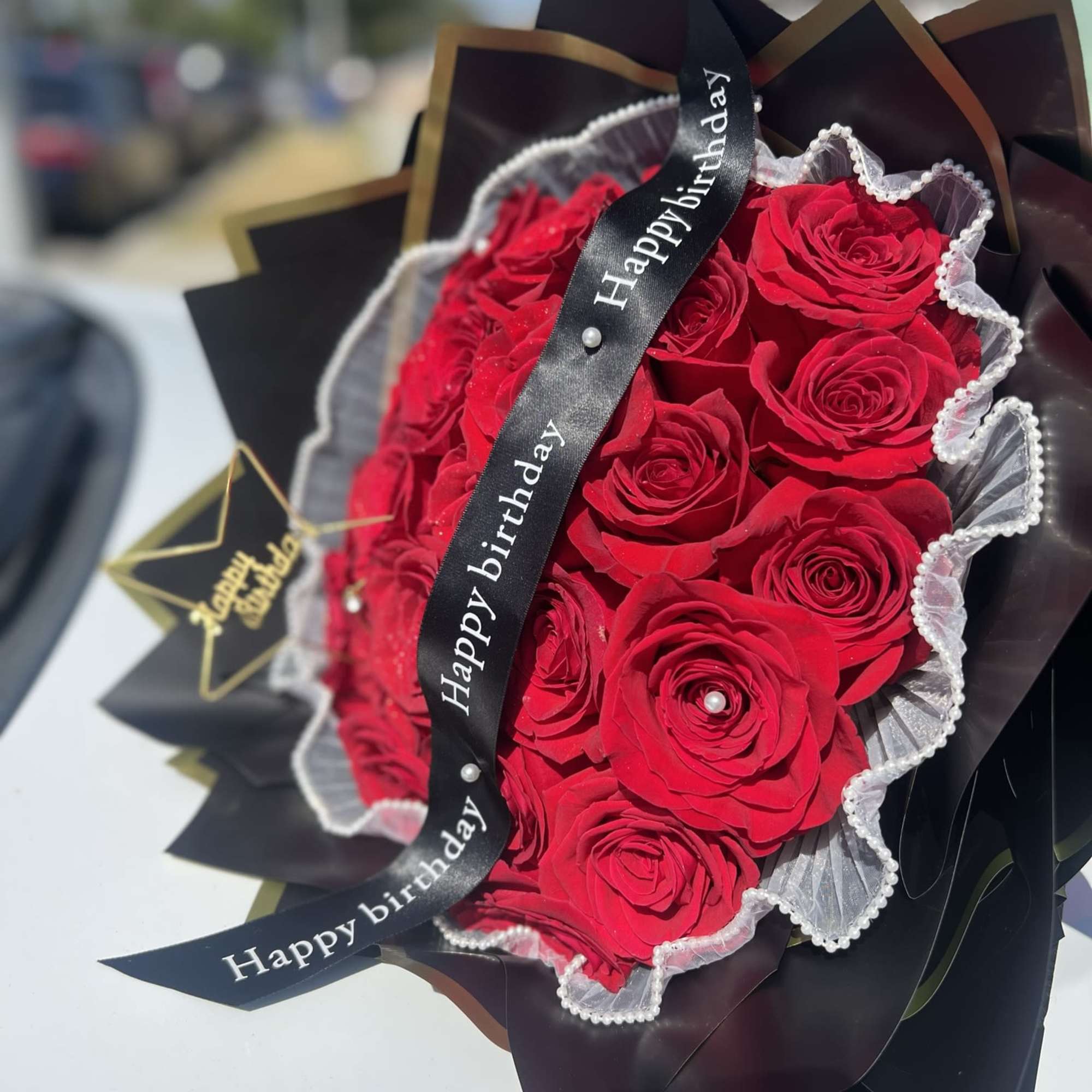 Bouquet of 24 red roses, ribbon and small sign included.