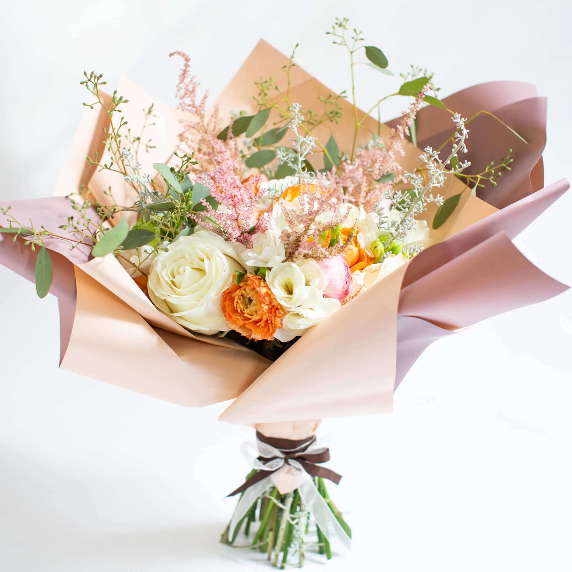 A hand-tied arrangement includes roses, hydrangeas, freesias, and ranunculus. A hand-tied arrangement includes roses, hydrangeas, freesias, and ranunculus.