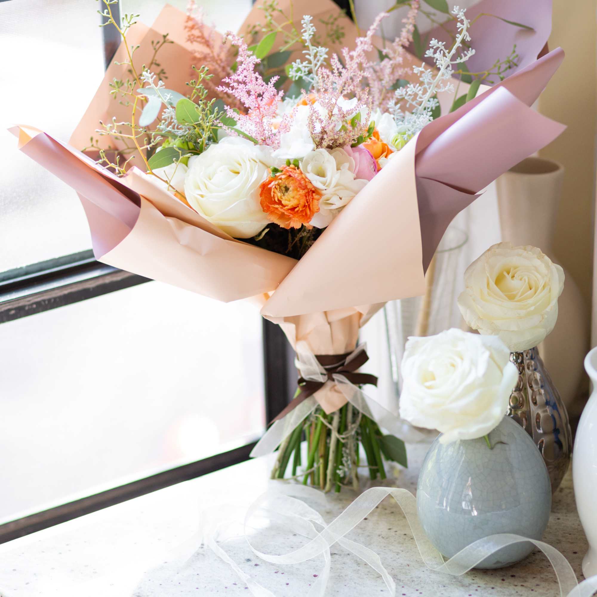 A hand-tied arrangement includes roses, hydrangeas, freesias, and ranunculus. A hand-tied arrangement includes roses, hydrangeas, freesias, and ranunculus.