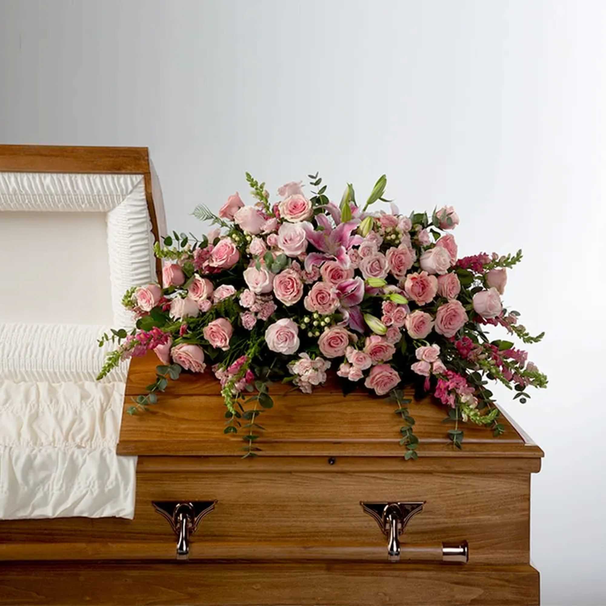 Roses, lilies, and more come together for a blushing pink half casket