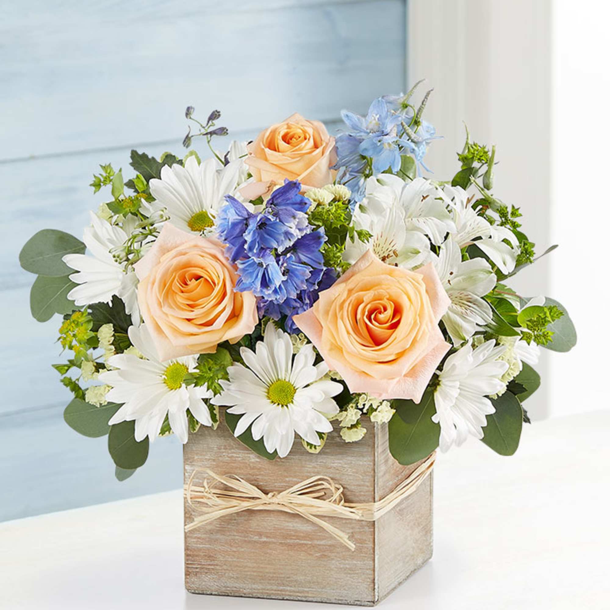 Artistically designed in a modern  wooden cube with peach roses, Bella