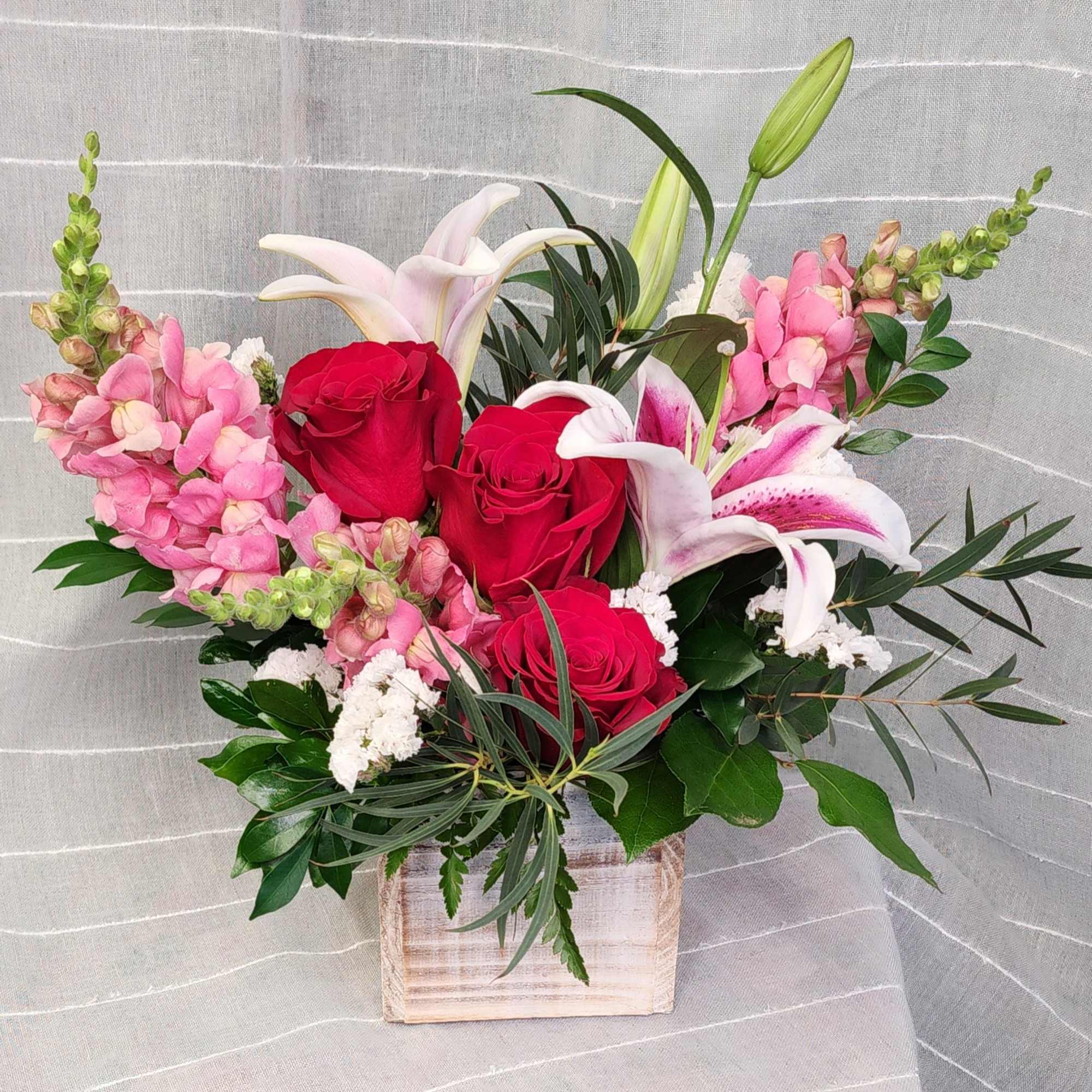 Snap dragons, oriental lilies, and roses.   A beautiful combination designed