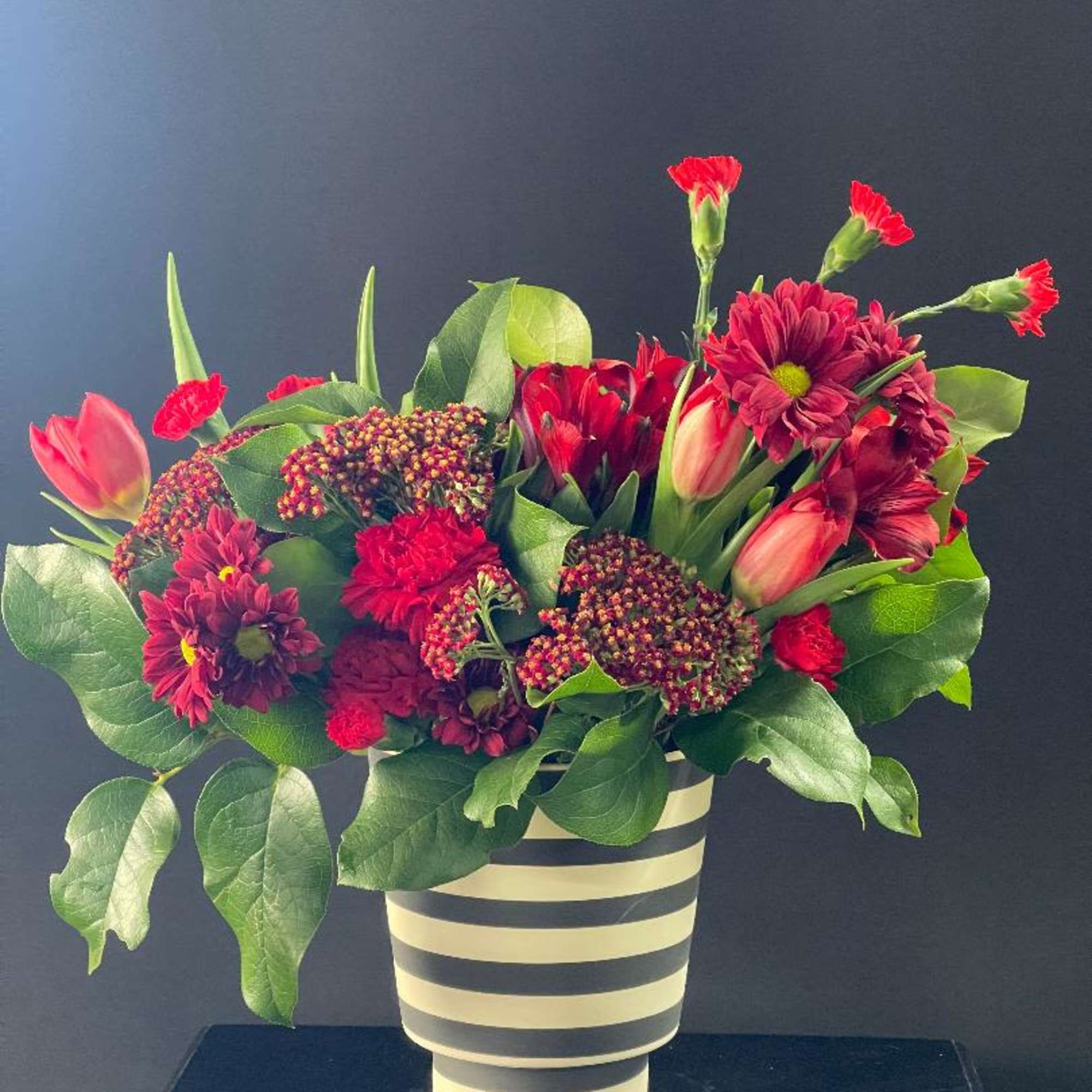 A mixture of reds in a fun striped container. 