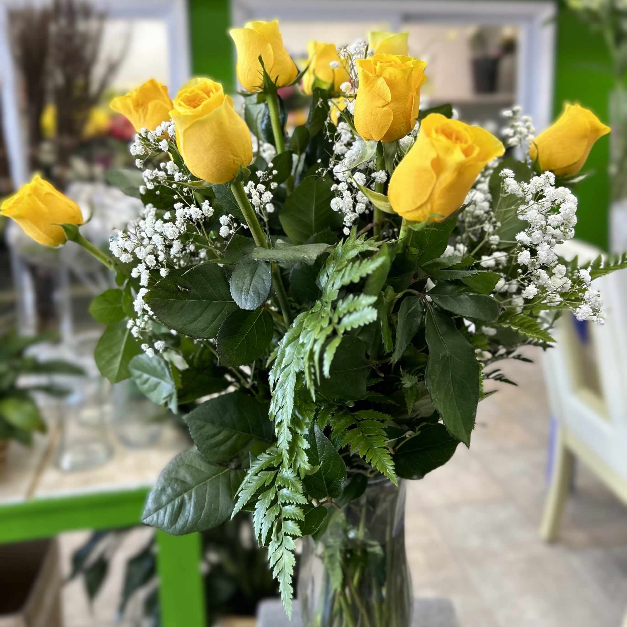 12 yellow roses in vase with baby's breath. More roses added as