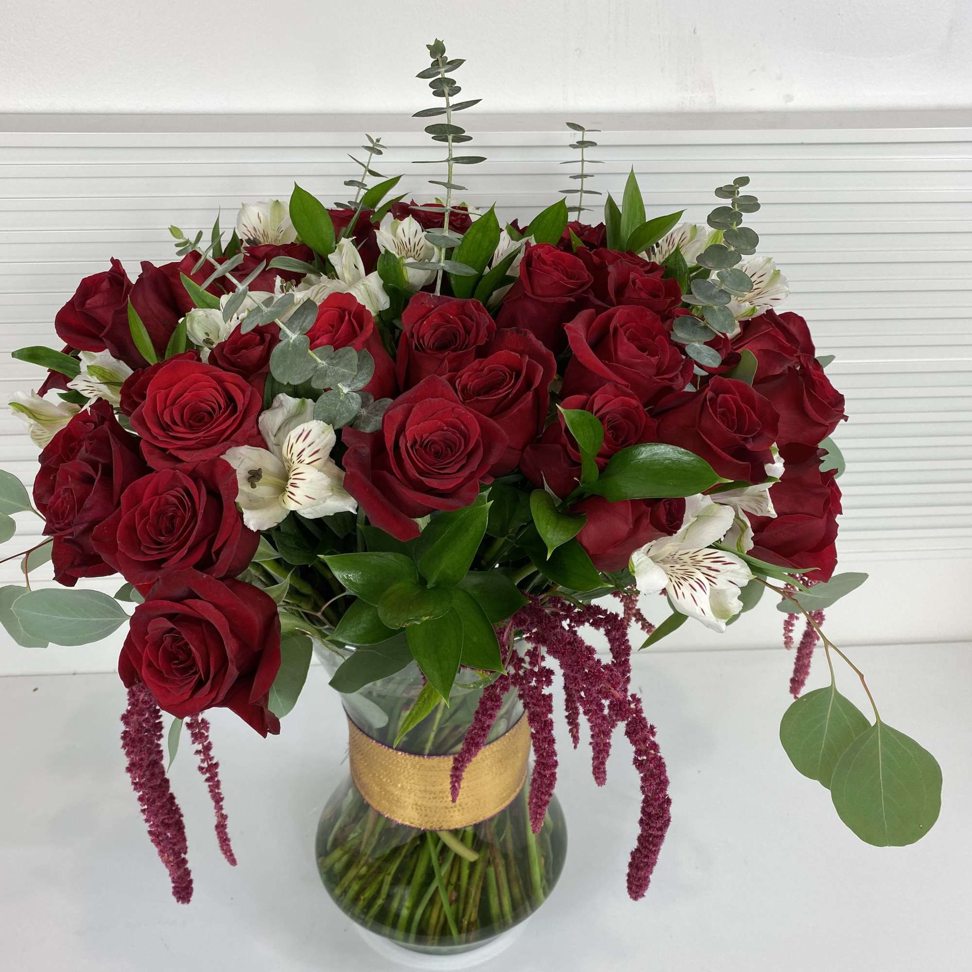 4 Dozen long stem red roses with white alstroemerias and rich greenery.