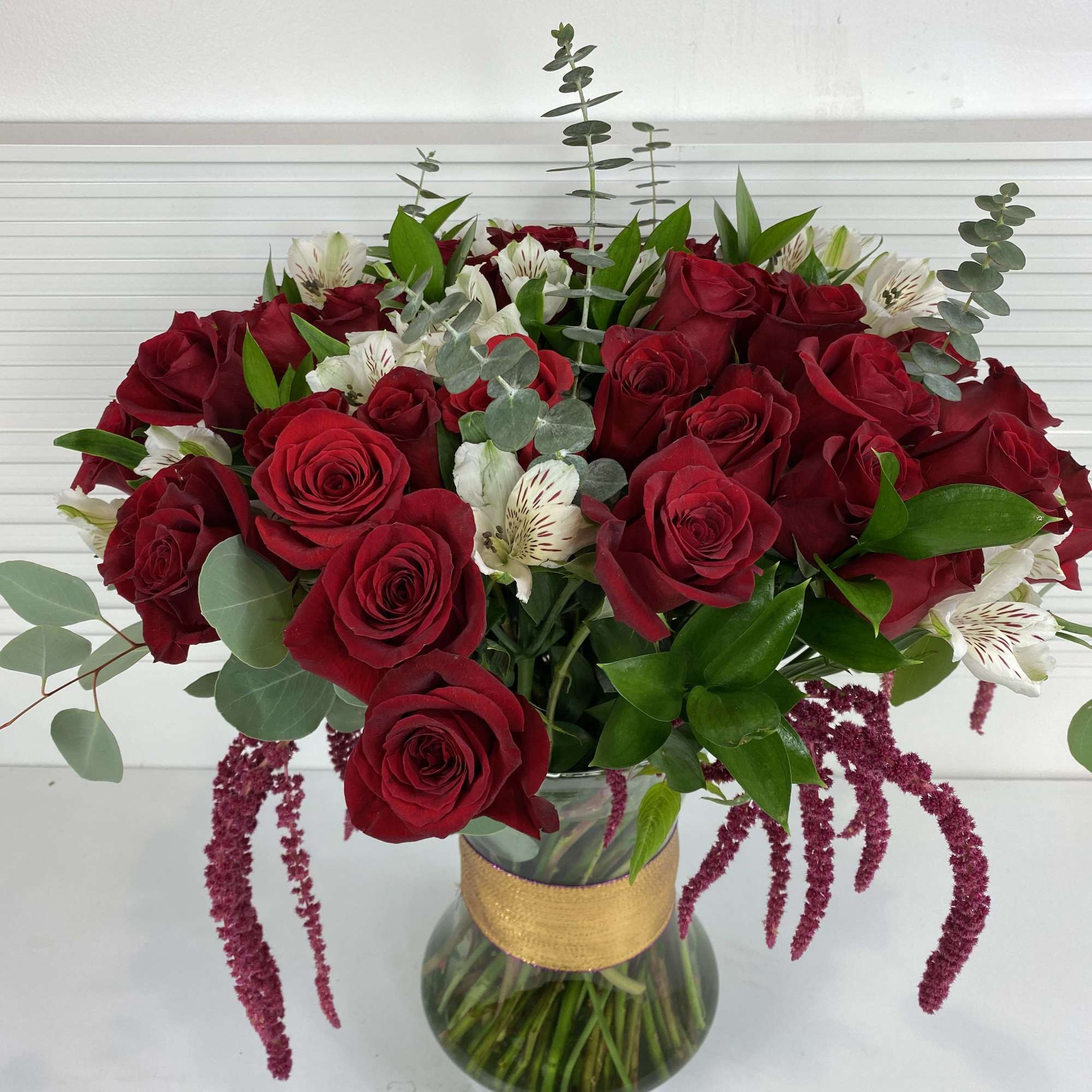 4 Dozen long stem red roses with white alstroemerias and rich greenery.