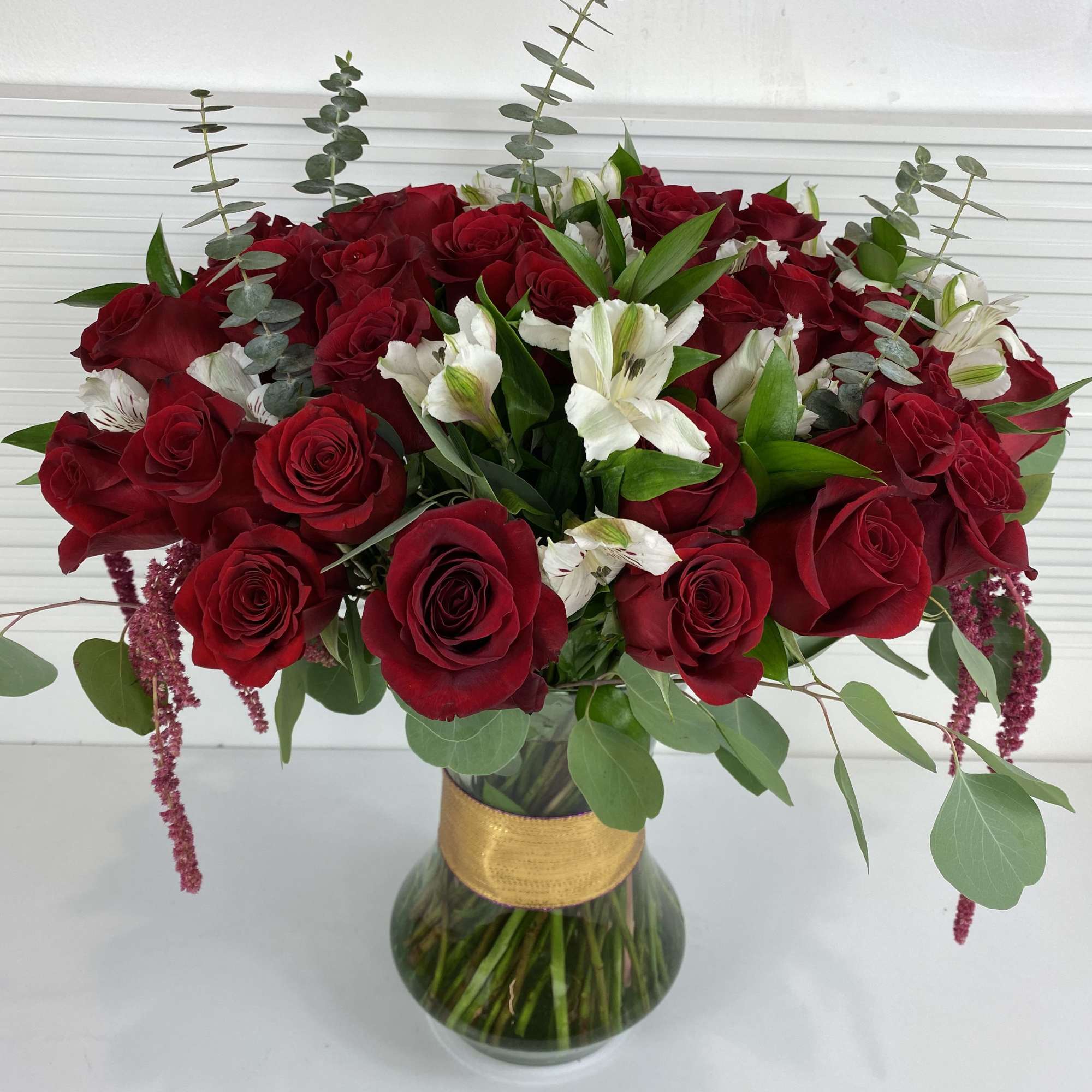 4 Dozen long stem red roses with white alstroemerias and rich greenery.