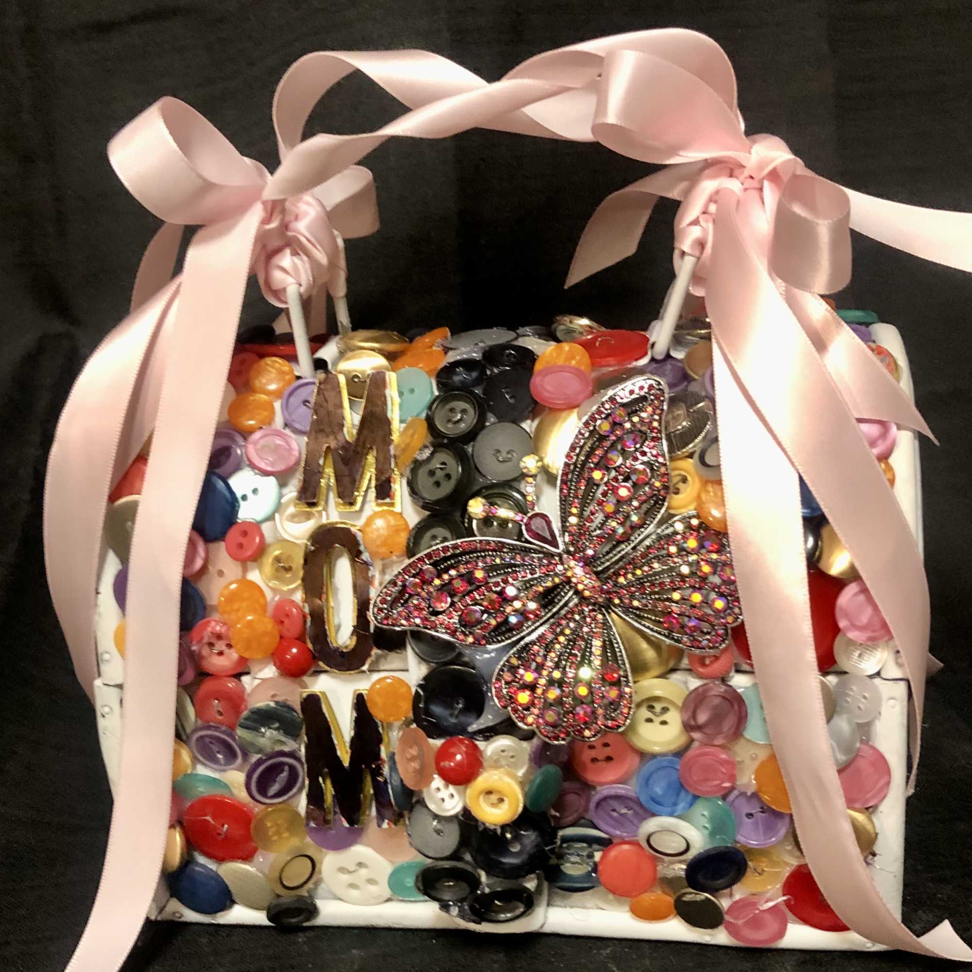 A small purse, embellished with assorted colored buttons, the word Mom and