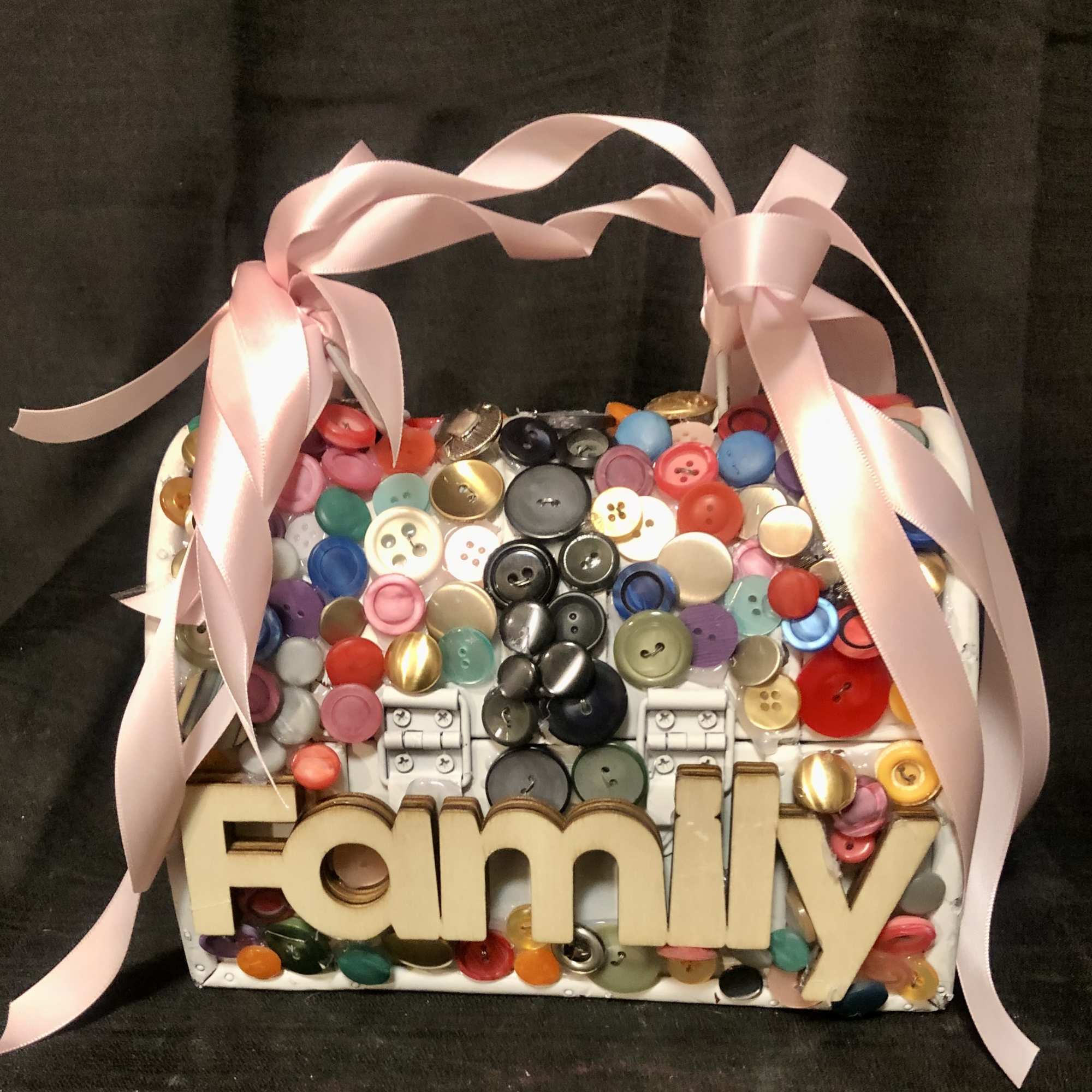 A small purse, embellished with assorted colored buttons, the word Mom and