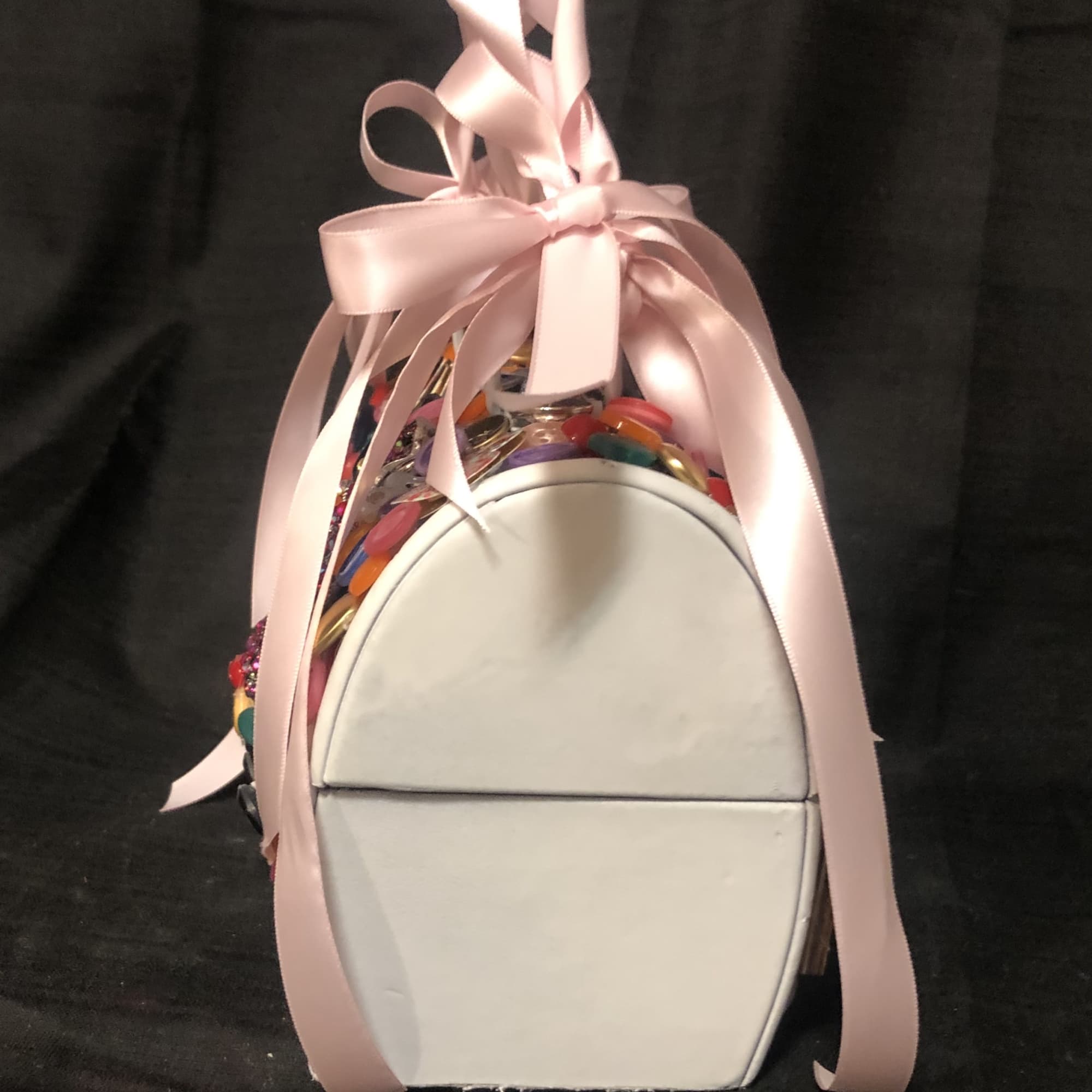 A small purse, embellished with assorted colored buttons, the word Mom and