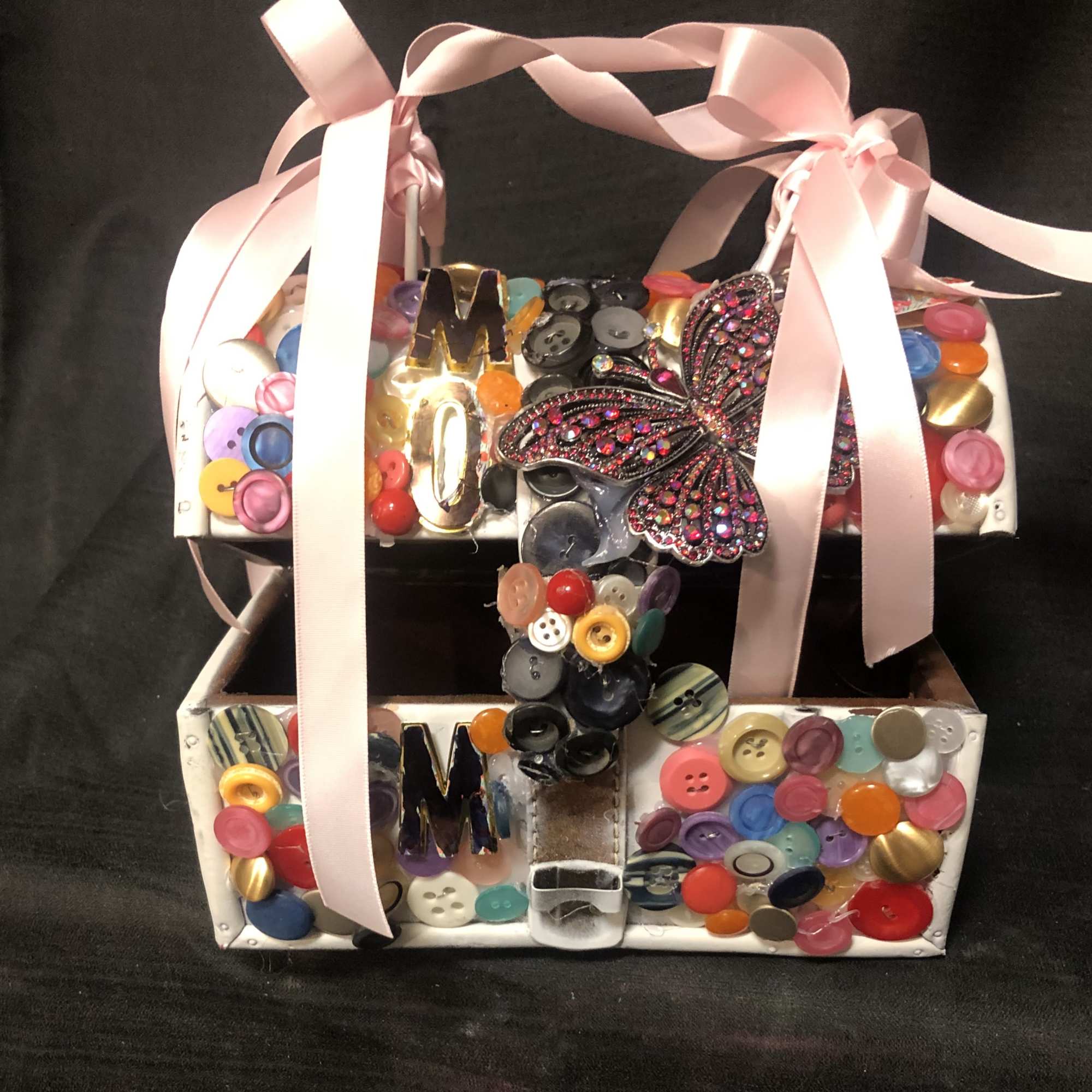 A small purse, embellished with assorted colored buttons, the word Mom and