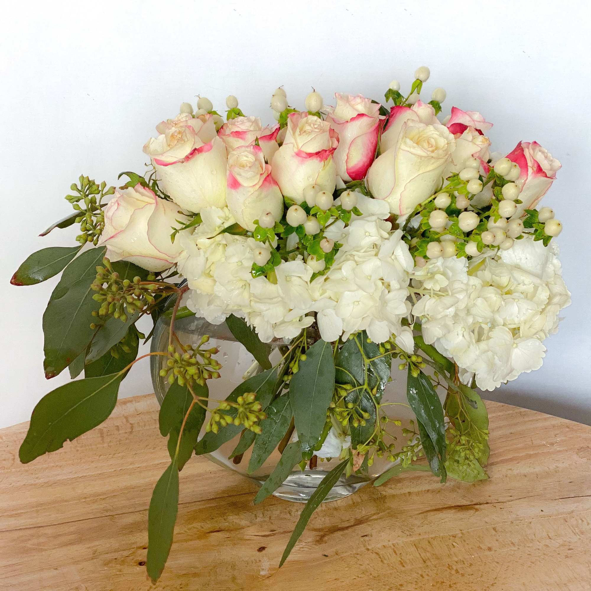 A dozen or 12 beautiful roses elegantly arranged on a bed of
