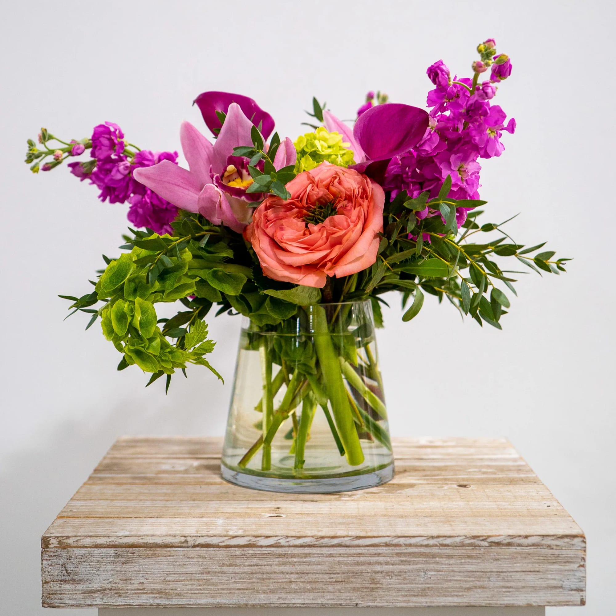 A beautiful compact arrangement of garden roses, mini green hydrangea, stock, cymbidiums