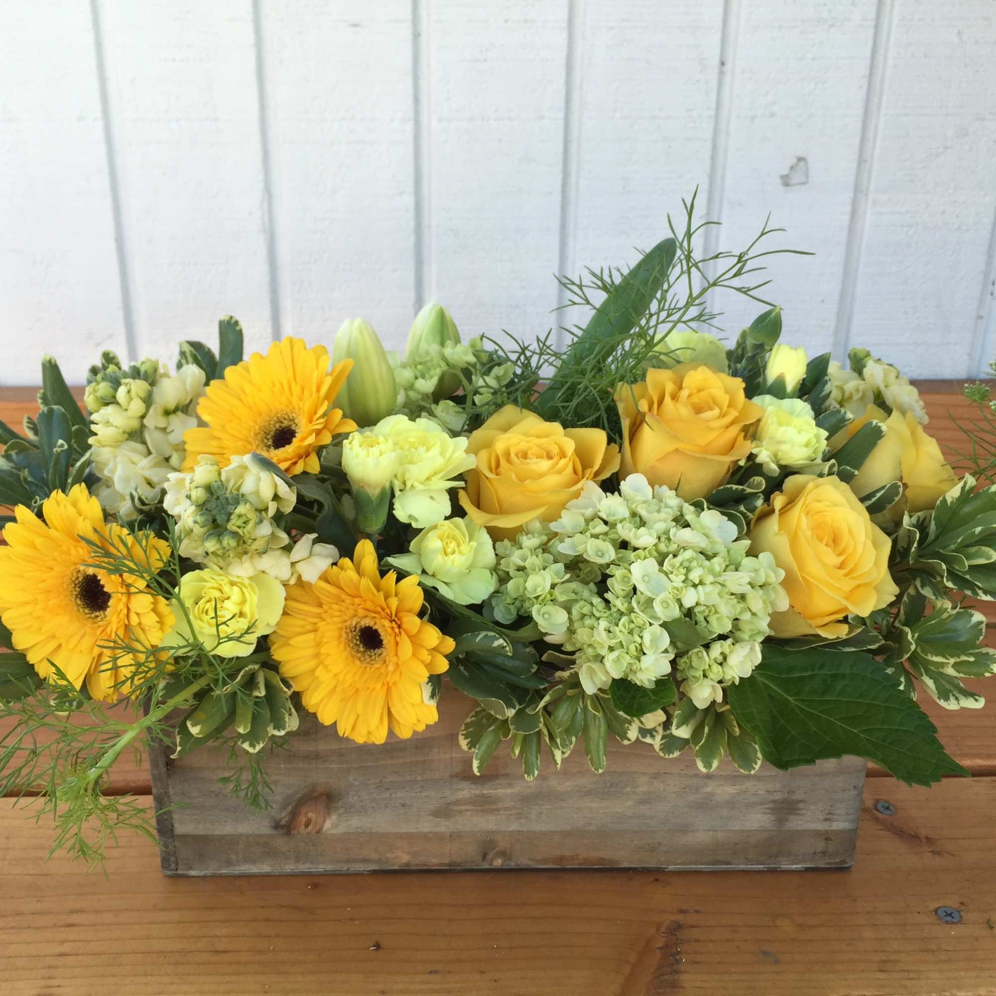 Beautiful vibrant yellow blooms in wooden rectangle box. Roses, gerbera daisies, stock Beautiful vibrant yellow blooms in wooden rectangle box. Roses, gerbera daisies, stock