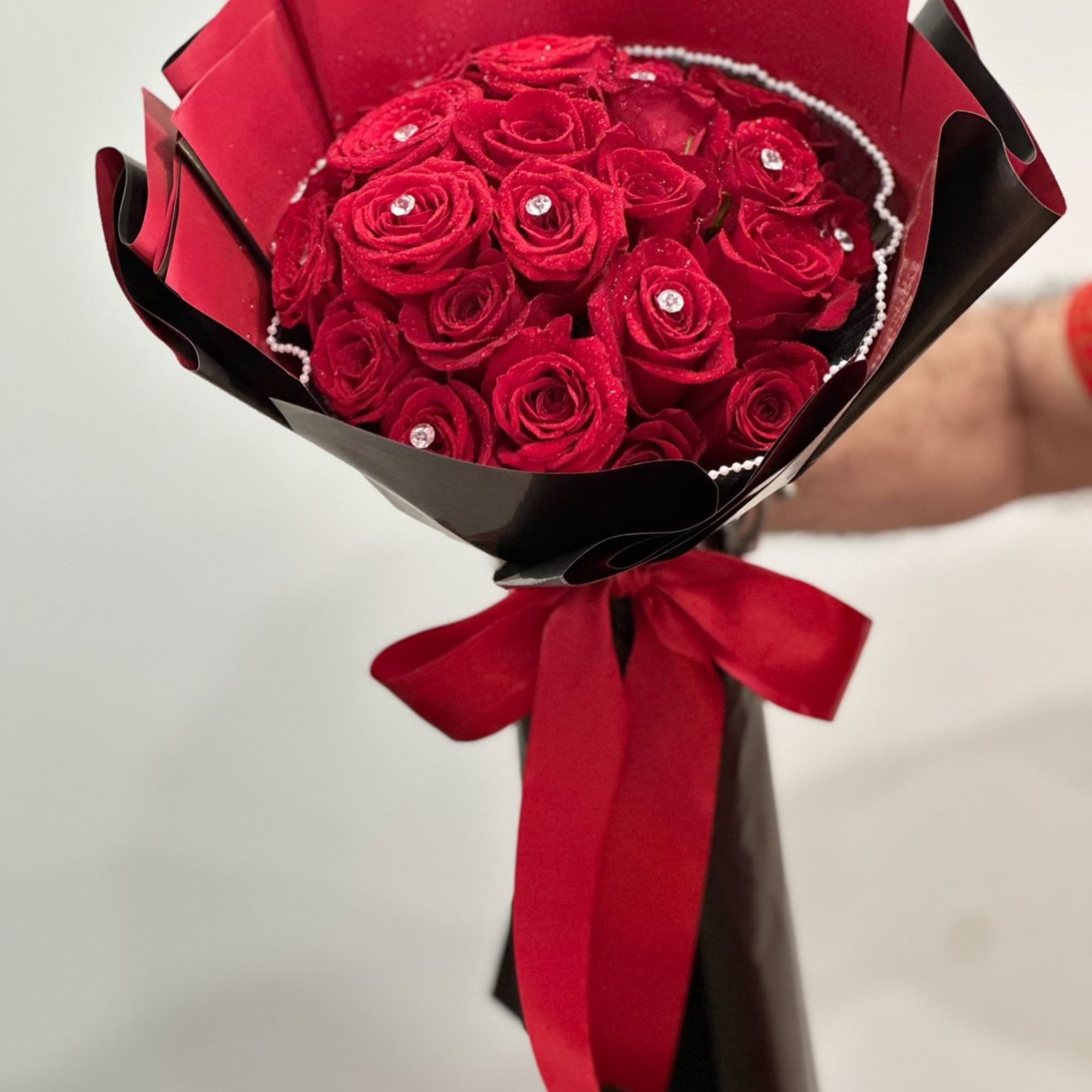A 24 bouquet of vibrant red roses adorned with delicate pearl accents