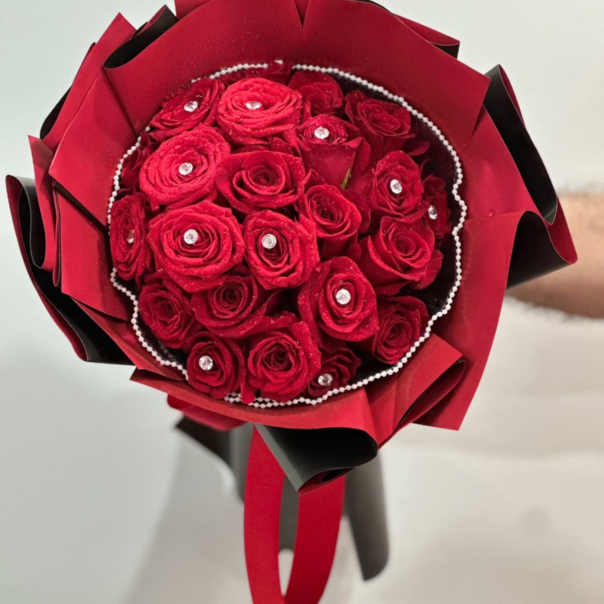A 24 bouquet of vibrant red roses adorned with delicate pearl accents