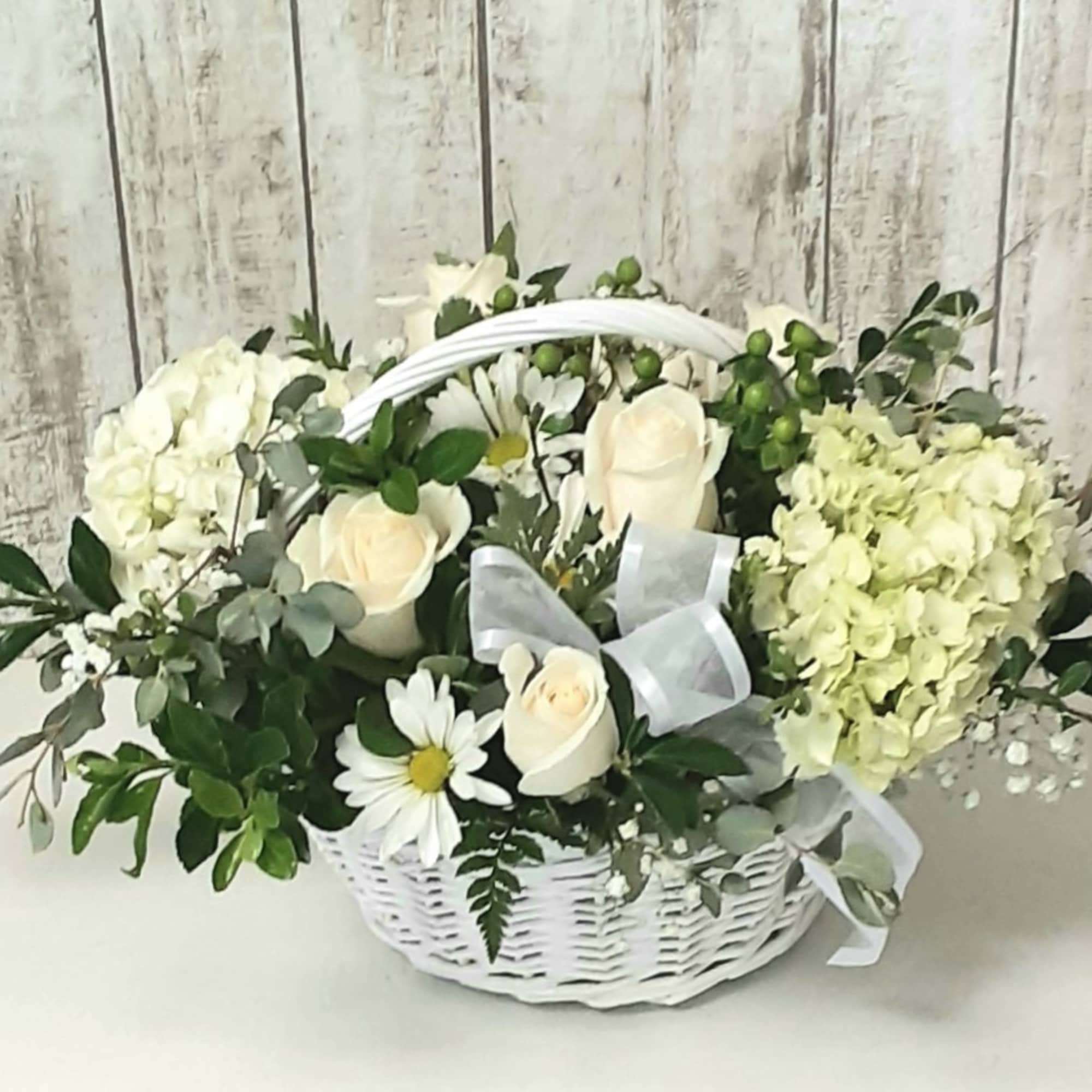 White hydrangeas ,roses and sweet daisies in a white basket with rich