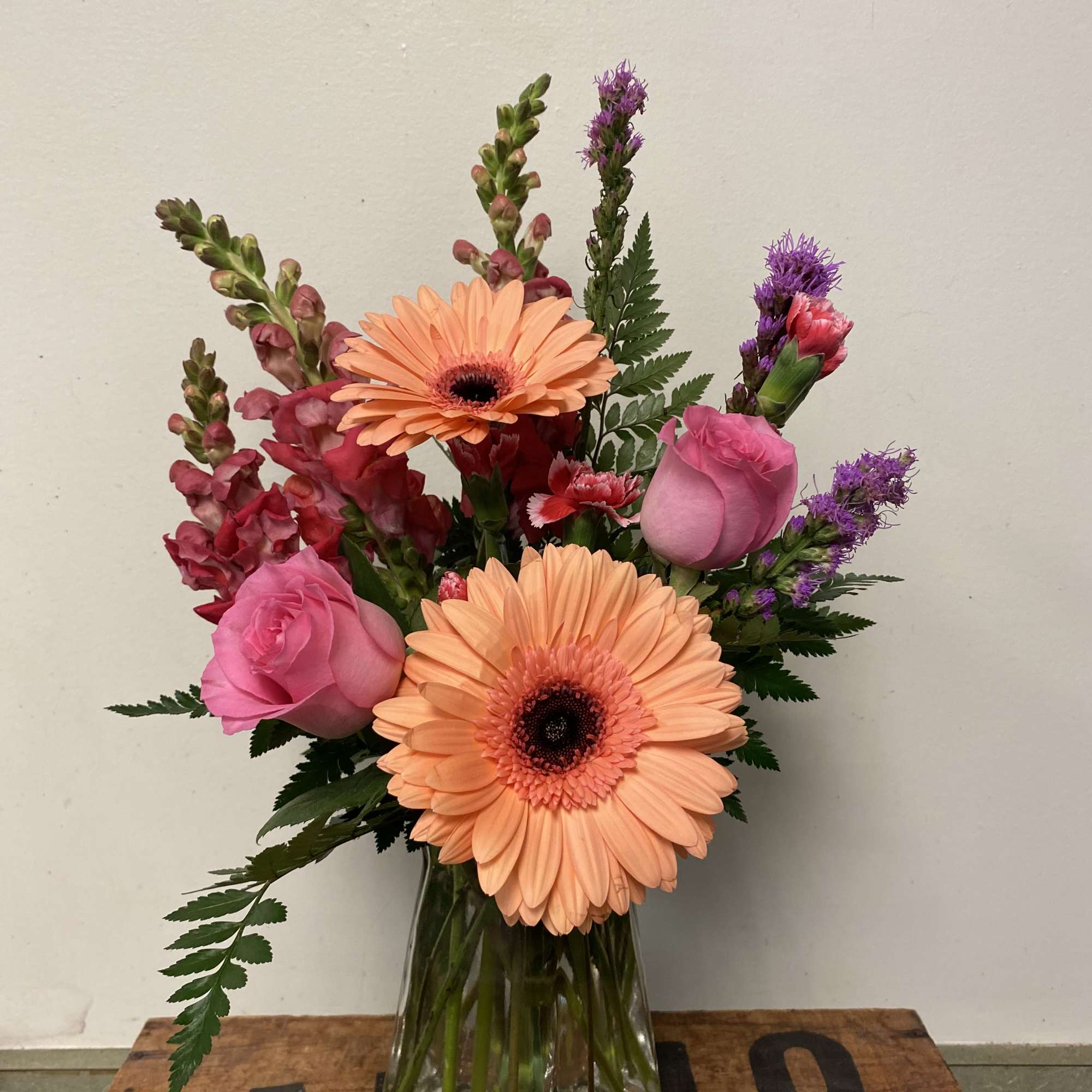Snapdragon, roses, miniature carnations, and liatris in pinks, purple, and peach in