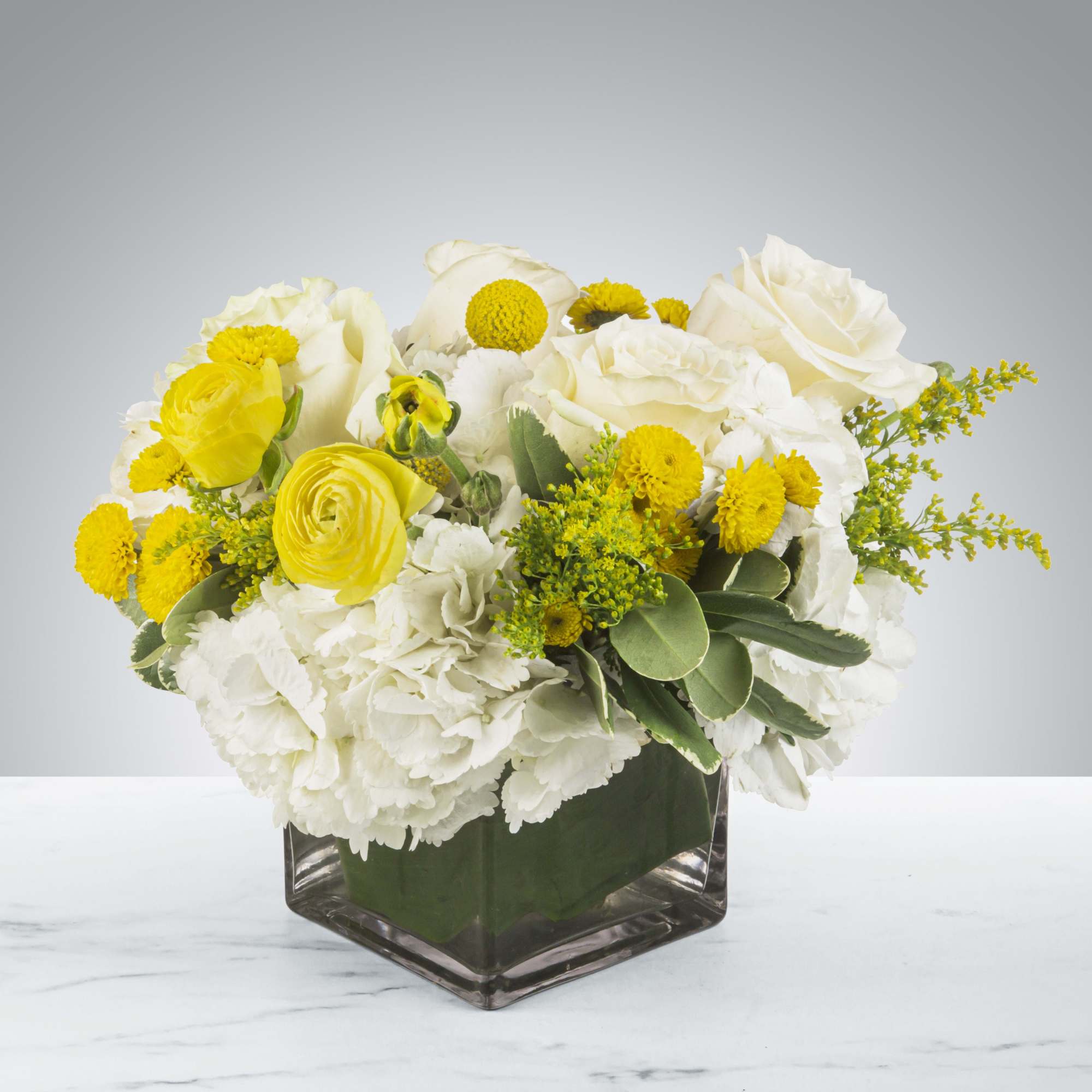 This white and yellow arrangement includes cream roses, button mums, and ranunculuses.