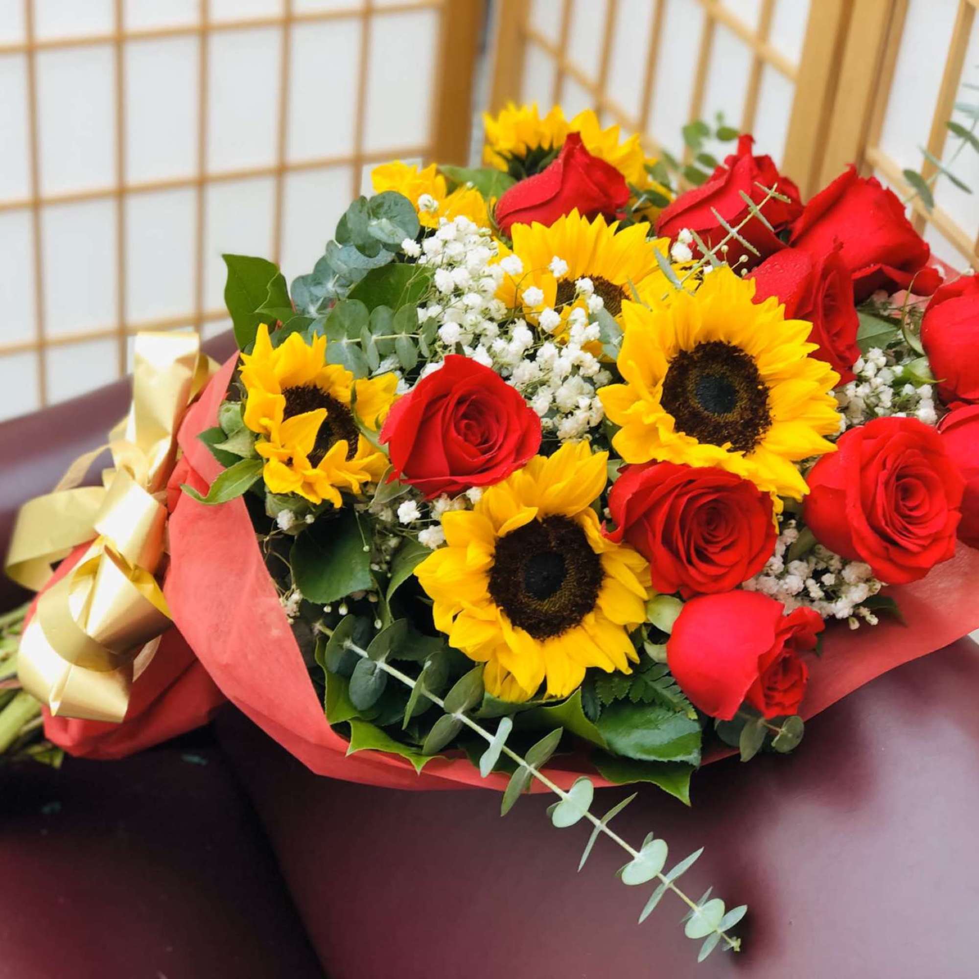 12 red roses, 6 sunflowers, babies-breath, greens, wrapped, with a large bow.
