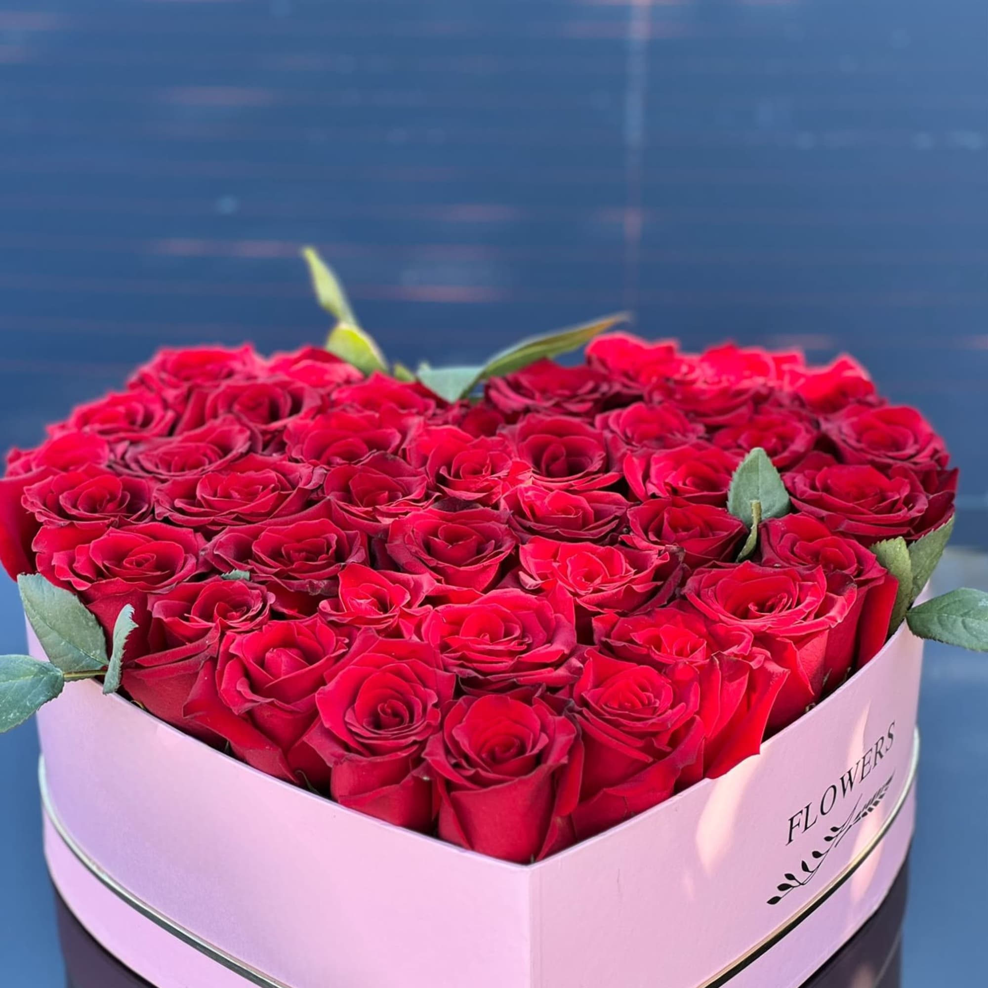Delicate red roses cradled in a heart-shaped hatbox, a flawless expression of