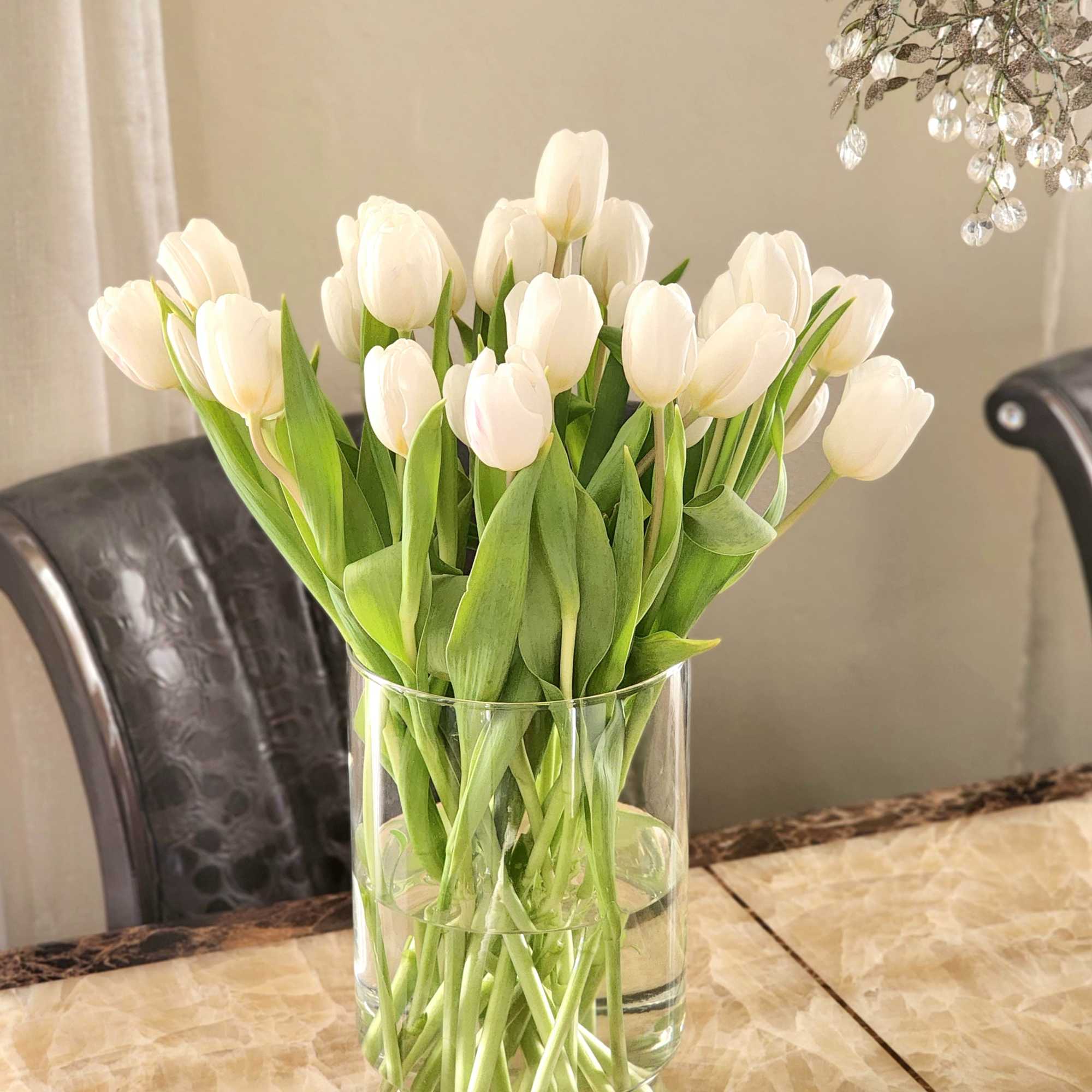This arrangement features pure white tulips, artfully designed in a modern glass
