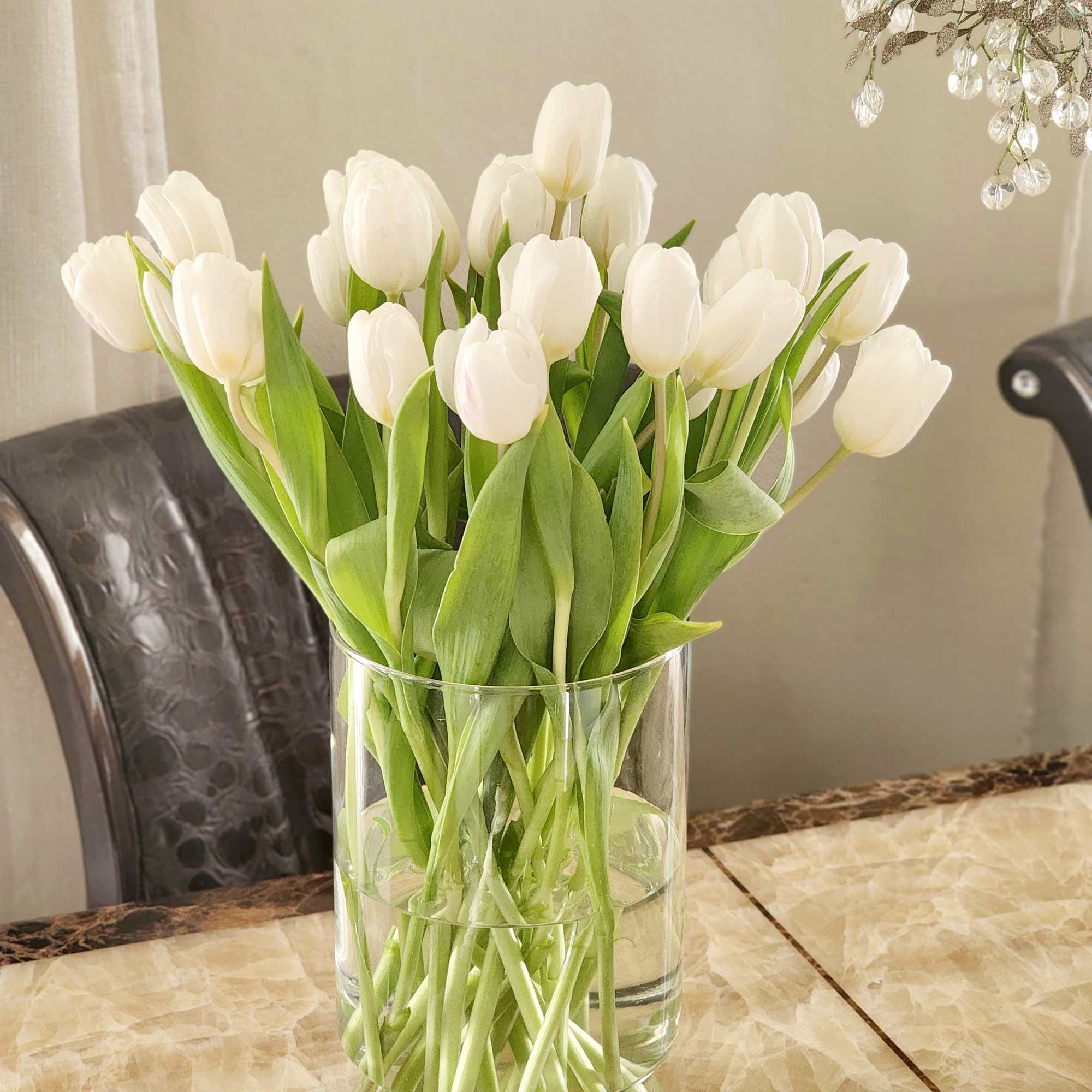 This arrangement features pure white tulips, artfully designed in a modern glass