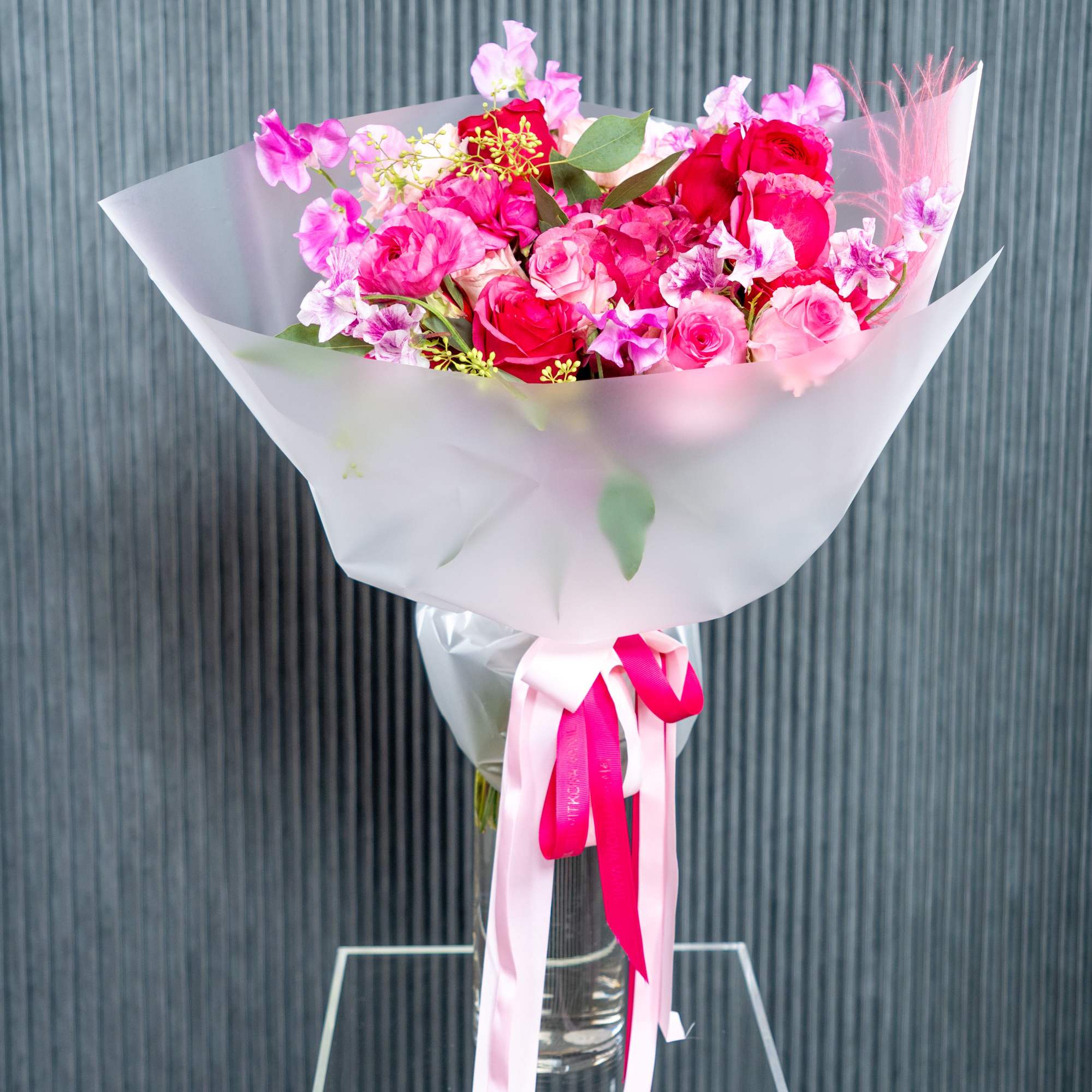 A delicate and charming arrangement of pink roses and sweet blooms, wrapped
